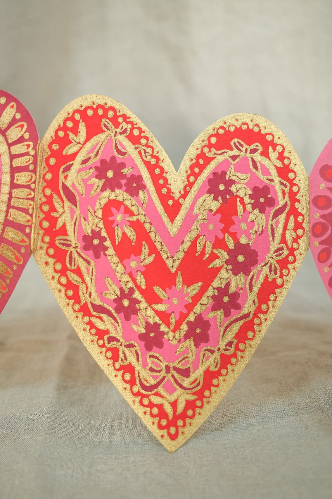 Decorative heart-shaped garland with floral patterns on a beige background.