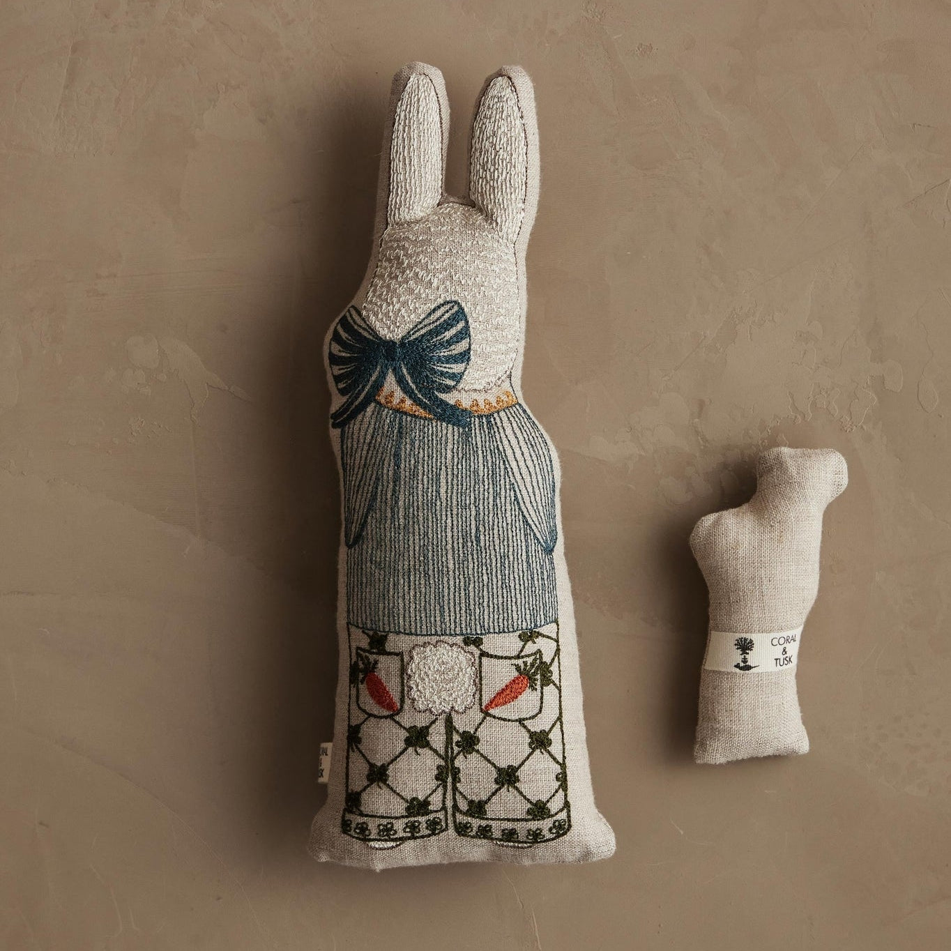 Plush rabbit figure with decorative elements on a beige background.