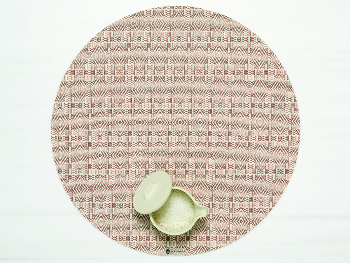 Boxwood Round Placemat with small container of grains on it in the Burnt Coral