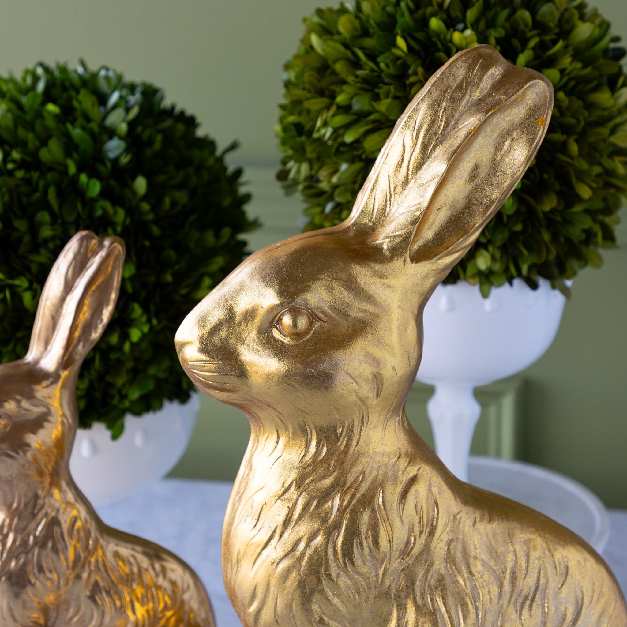 Gold rabbit statues with green foliage in the background.