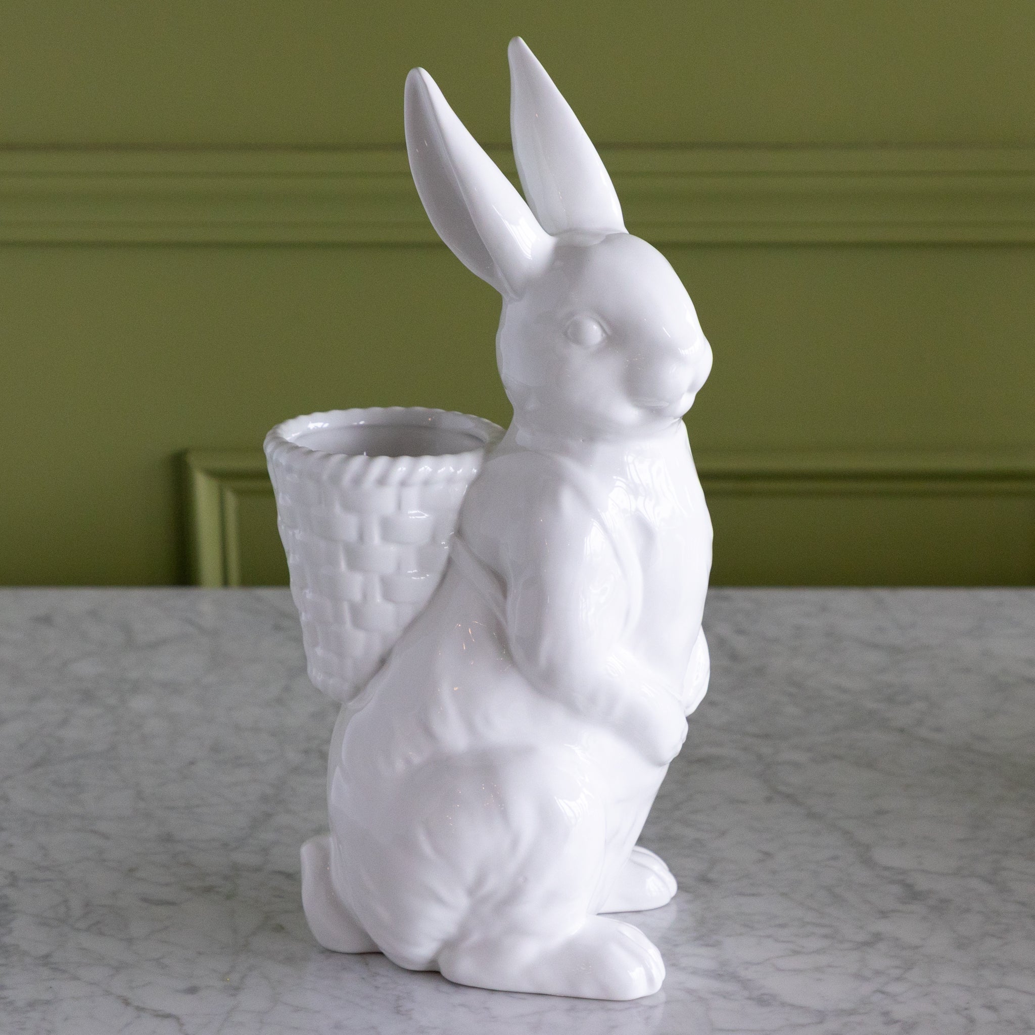 White ceramic rabbit planter on a marble surface with a green wall background.