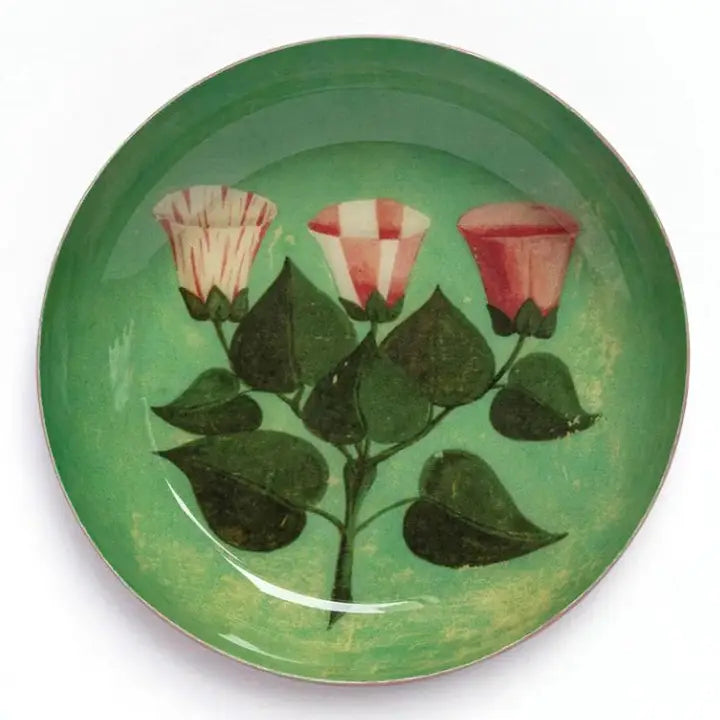 A green enamel plate with illustrated pink florals on a white background.