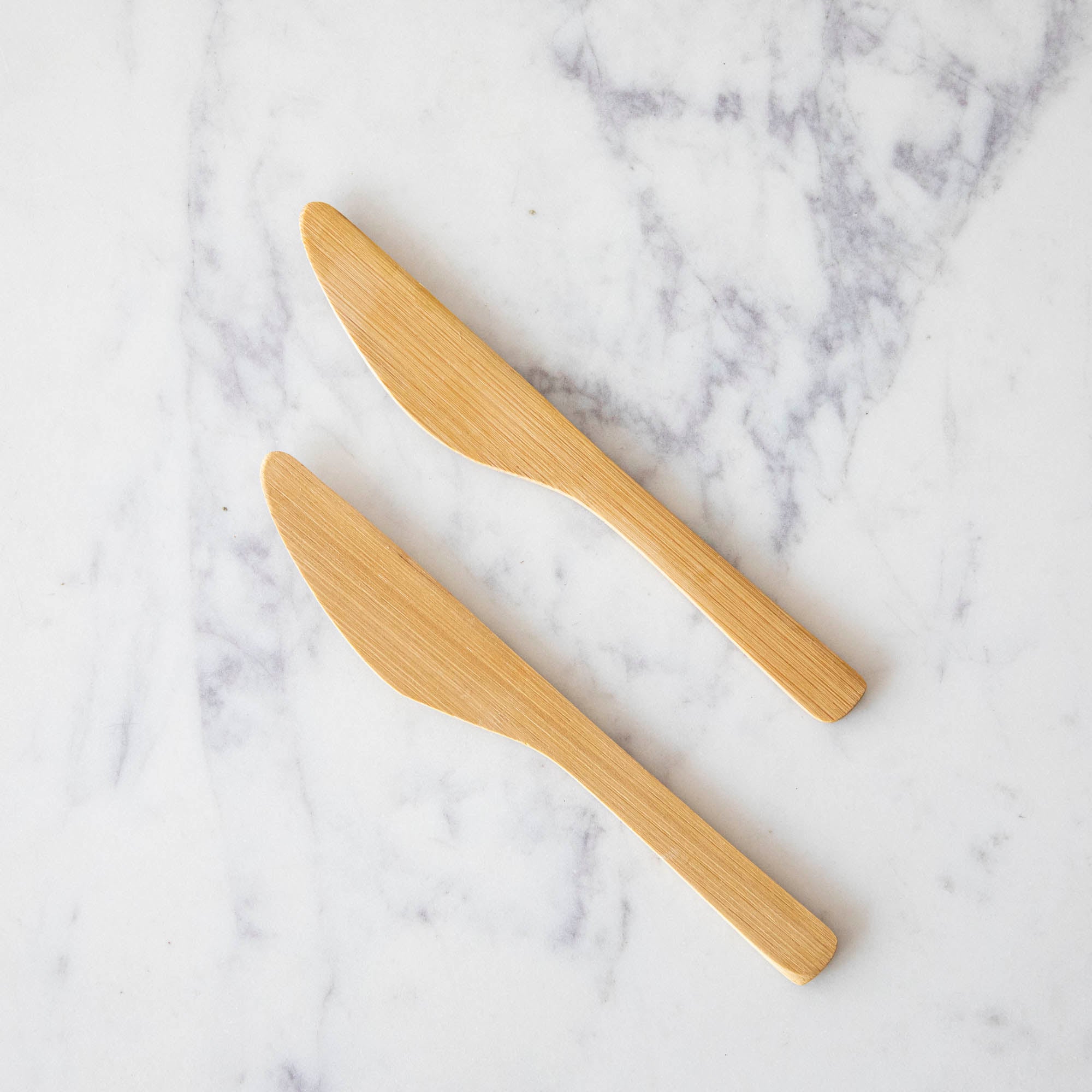 Two mini Bamboo Spreaders on a marble table.