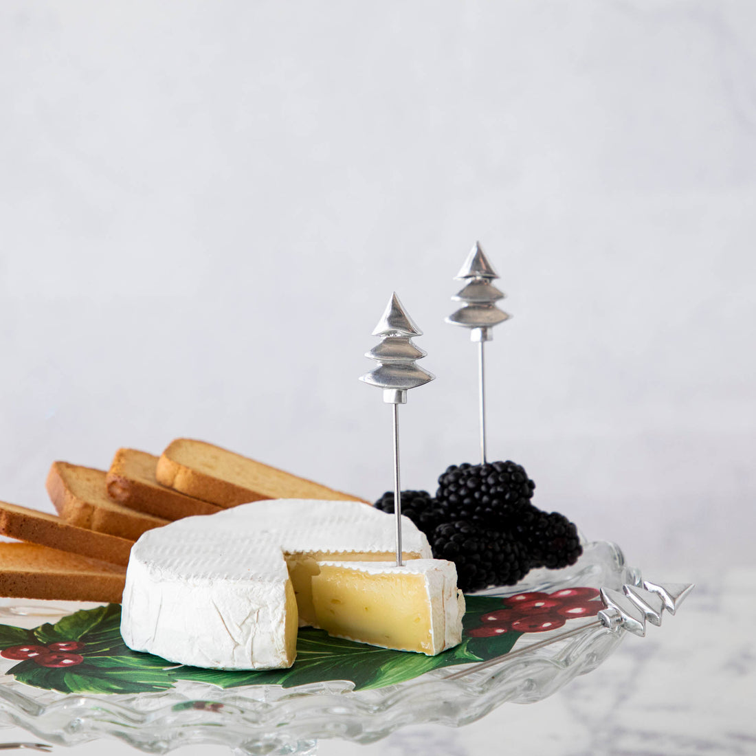 A cheese platter with brie, blackberries, and toast, decorated with Karma Holiday Cocktail Picks, Set of 4.