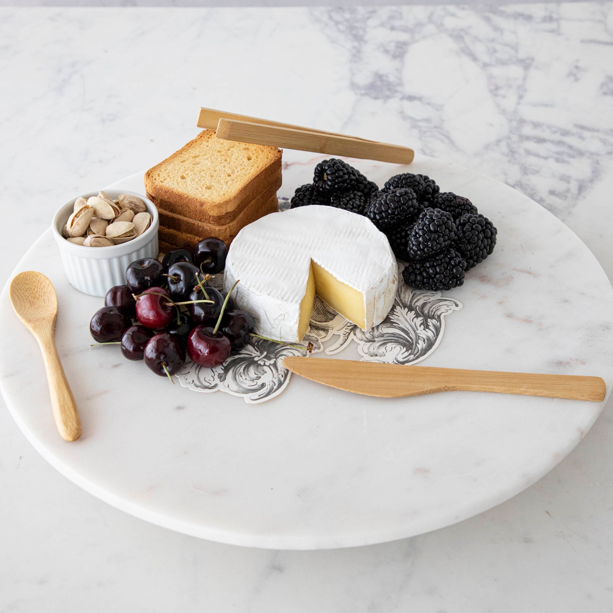 A plate with cheese, fruit, and nuts on it, served with BIA Mini Bamboo Utensils.