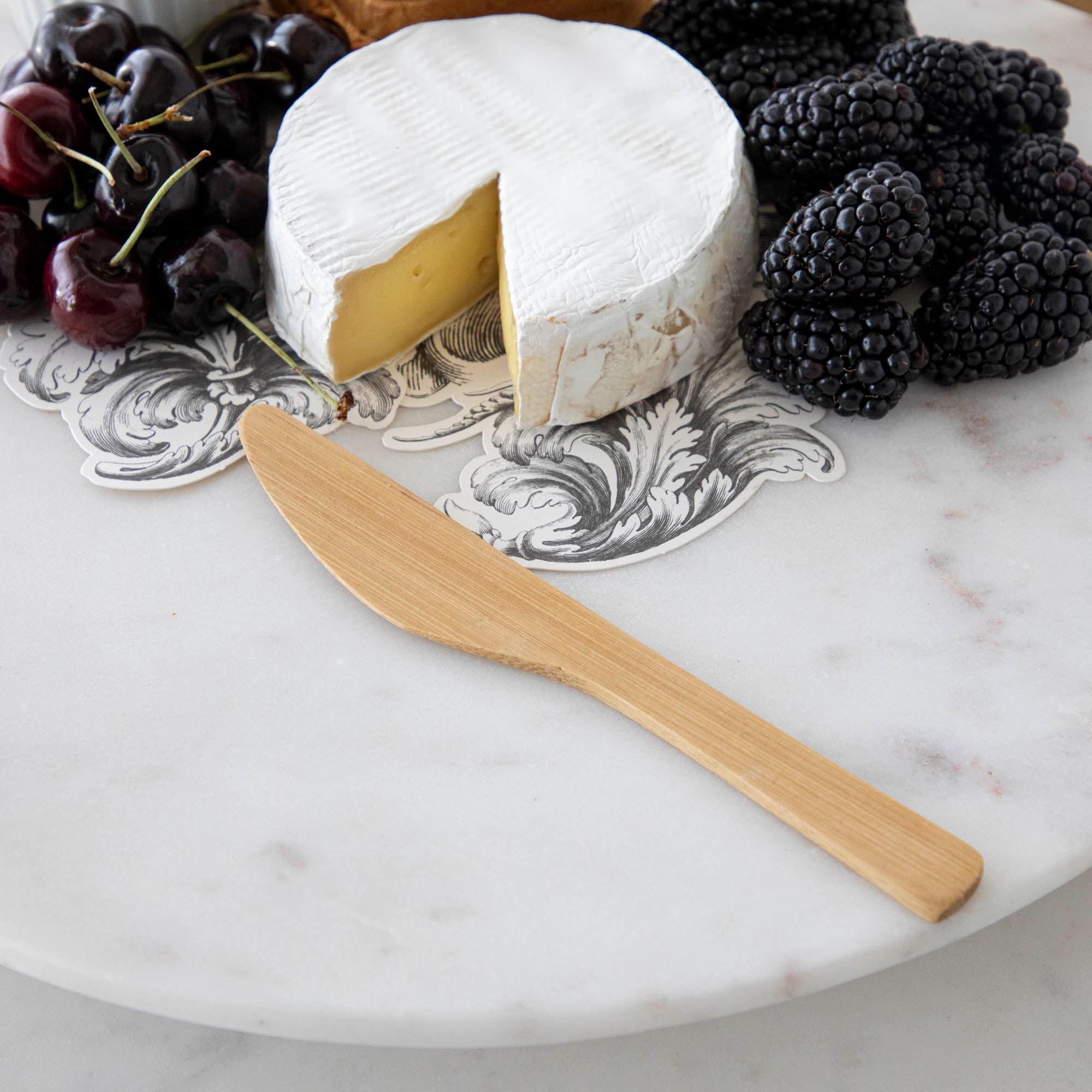 A plate with cheese, fruit, and nuts on it, served with BIA Mini Bamboo Utensils.