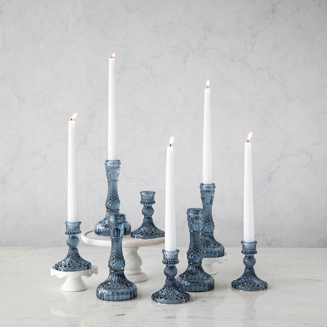 A group of Accent Decor Vintage Blue Candlestick candle holders on a marble table.