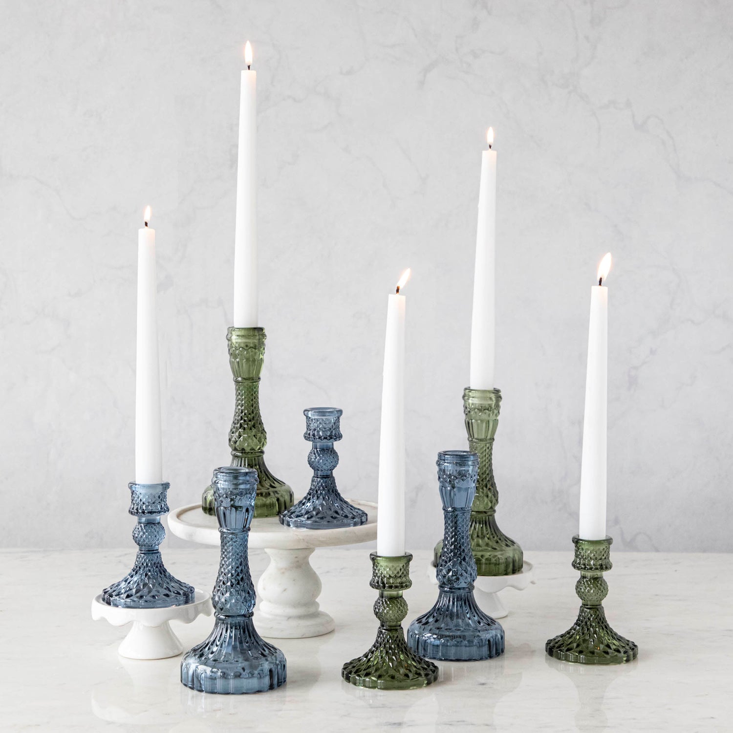 A group of Accent Decor Vintage Blue Candlestick candle holders on a marble table.
