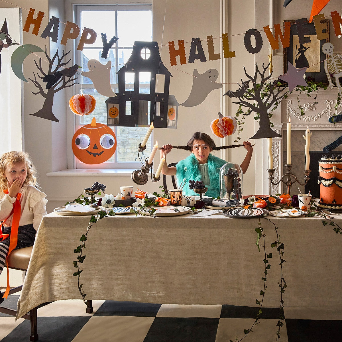 Children at a Halloween-themed table with decorations and &