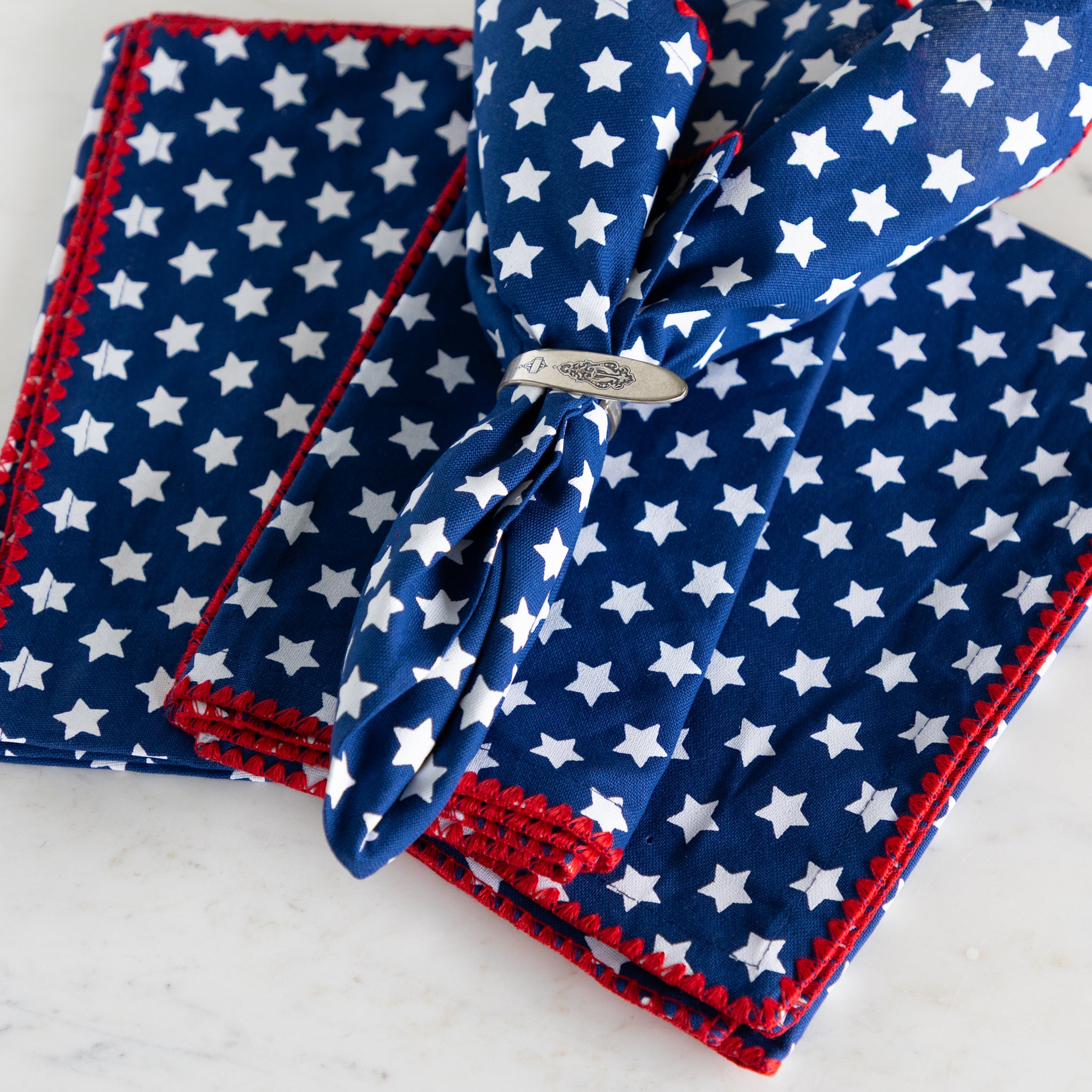 Blue napkin with white star pattern and red border on a white background.