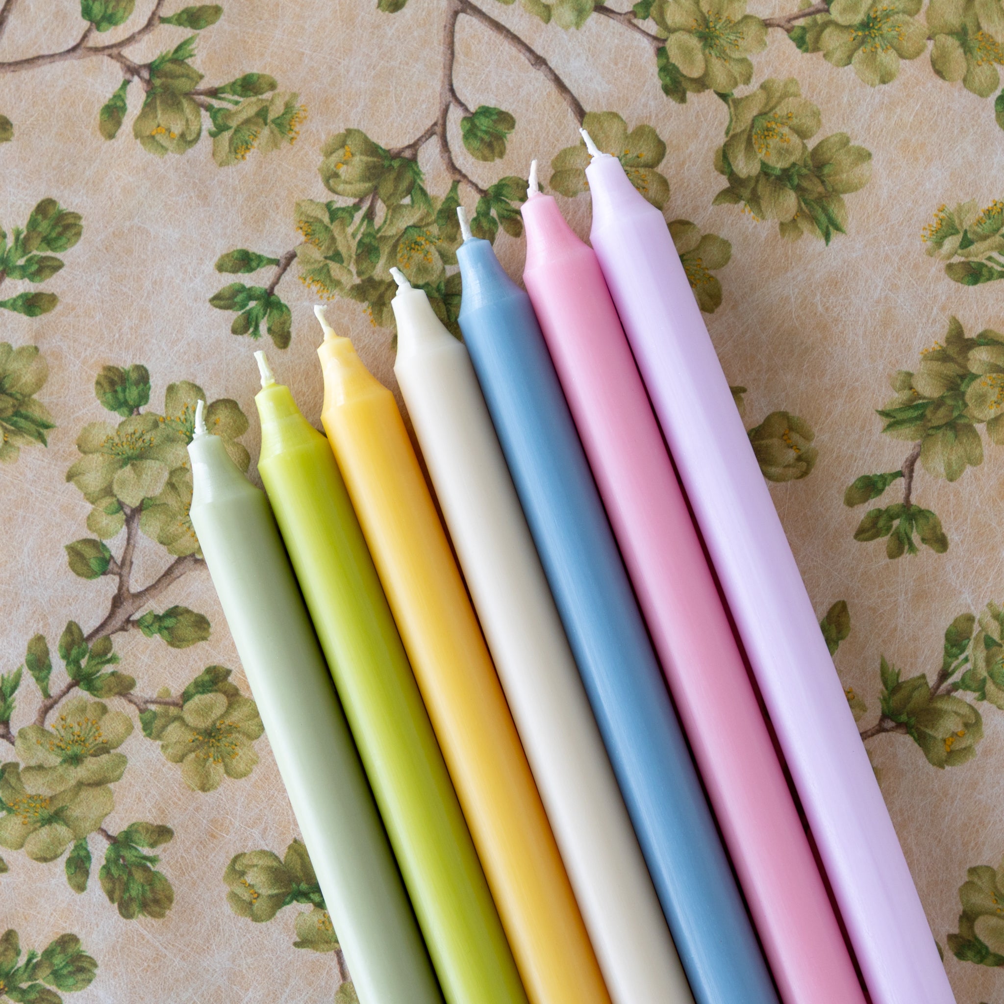 Set of colorful candles on a floral-patterned background.