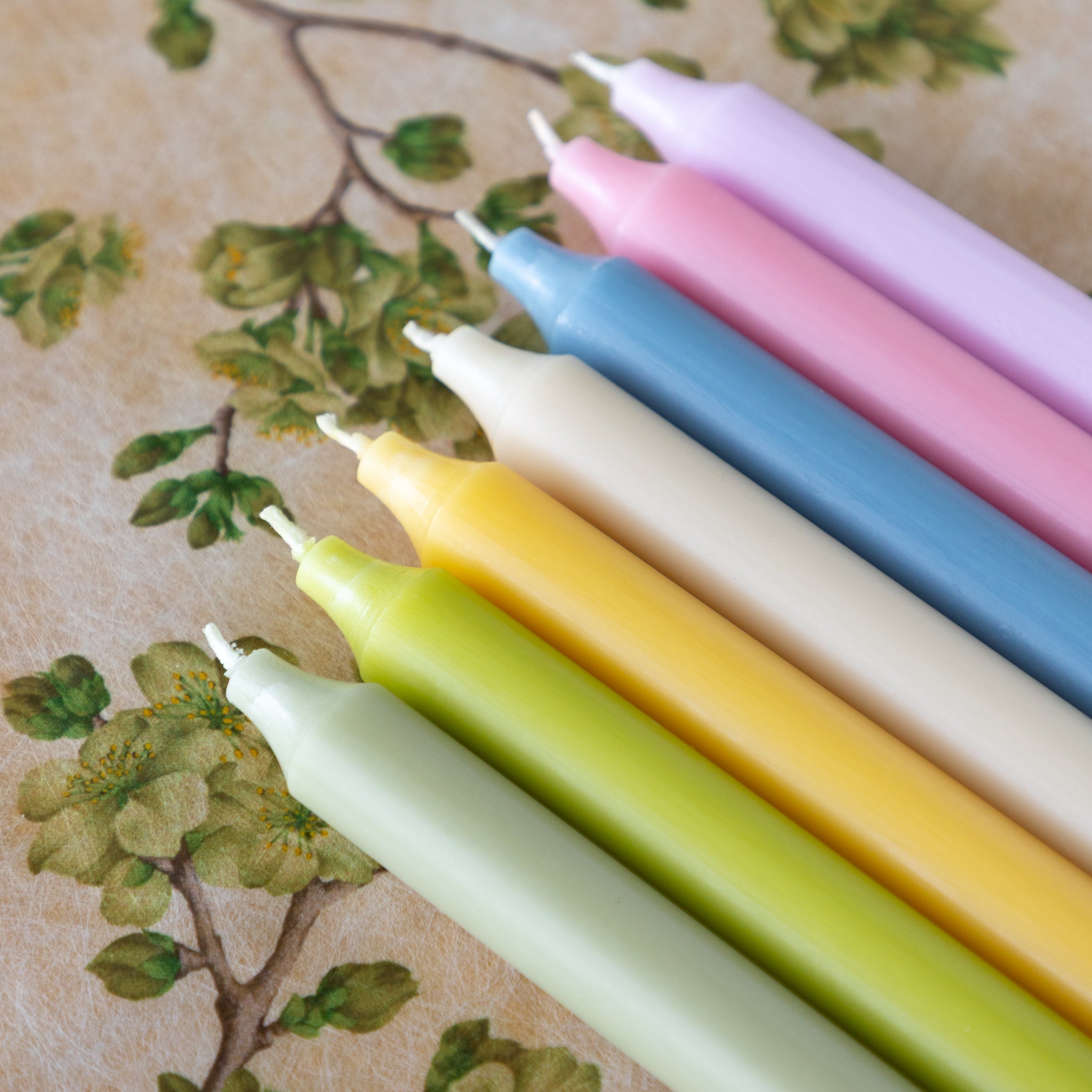 Set of colorful candles on a floral-patterned background.