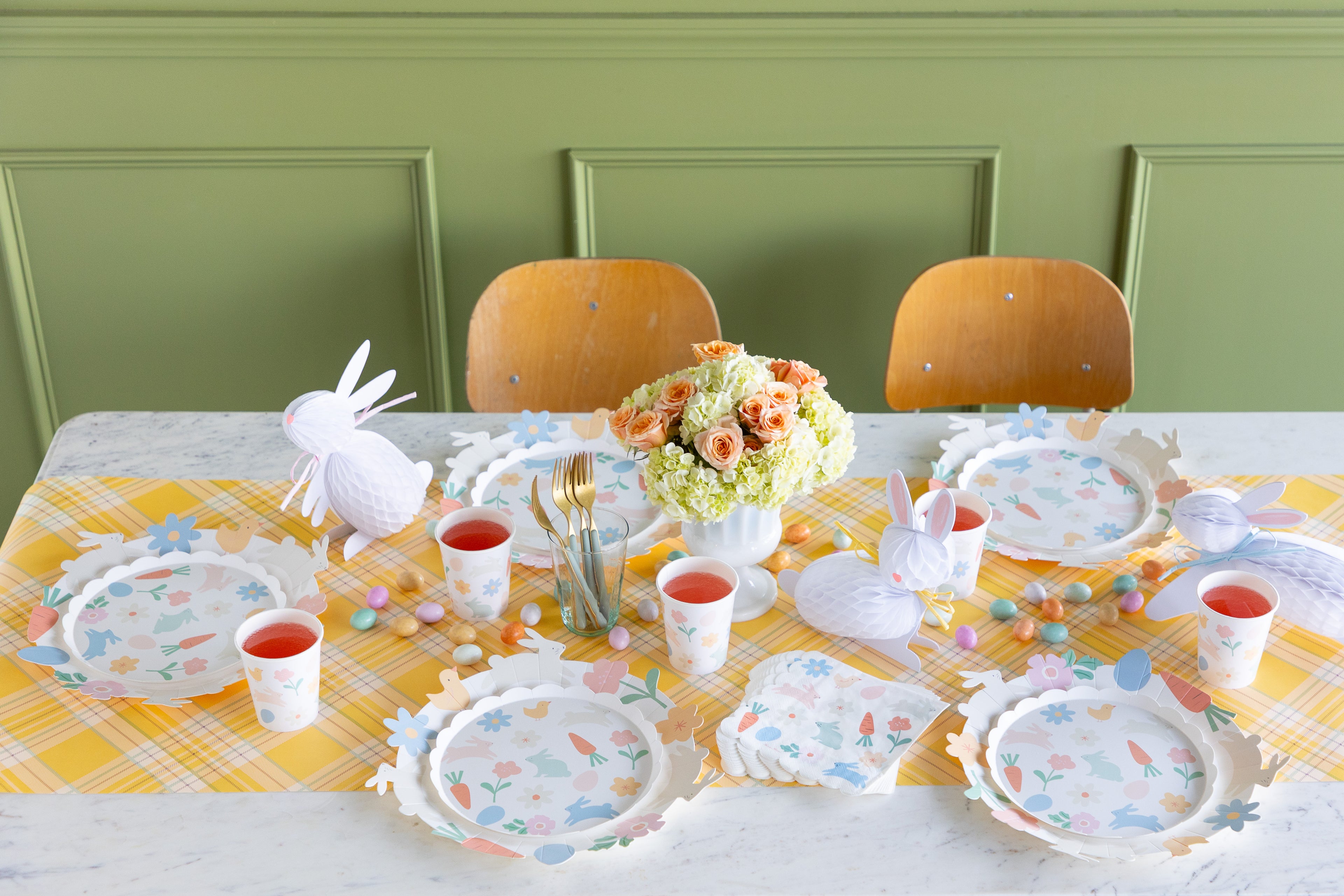 Easter-themed table setting with bunny decorations, colorful plates, and a green wall background.