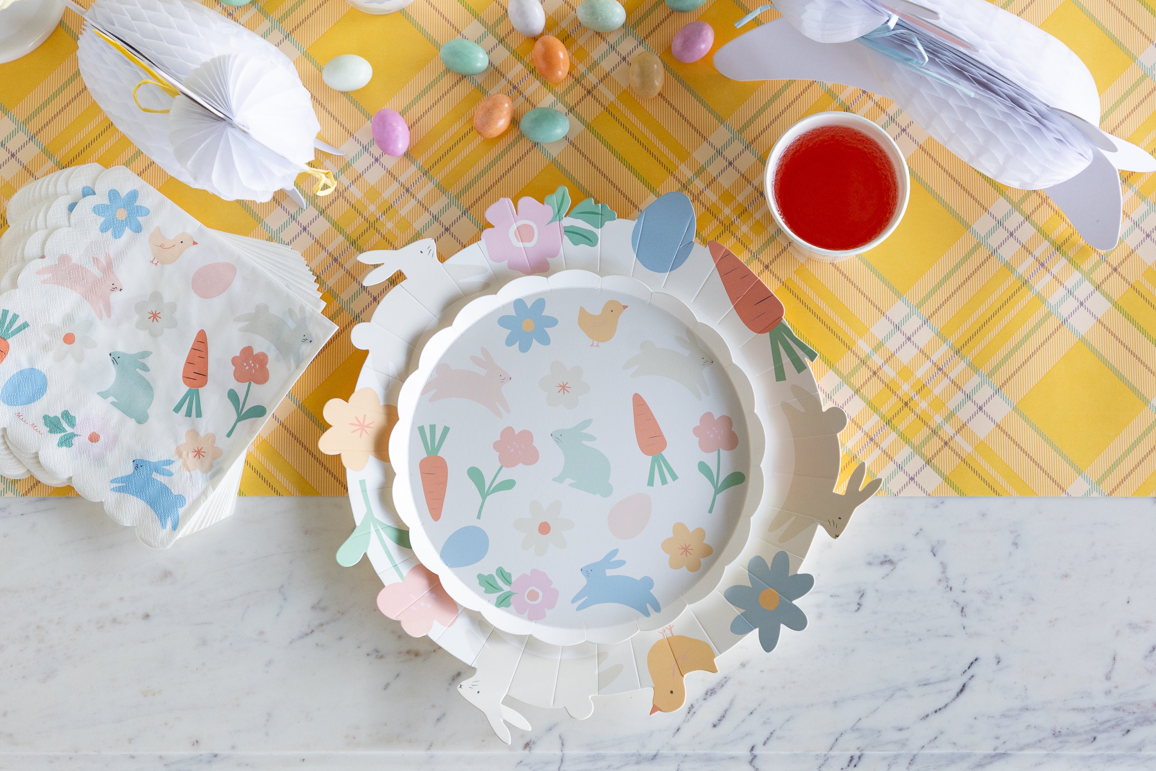 Easter-themed plates with bunny and carrot designs on a yellow checkered tablecloth.