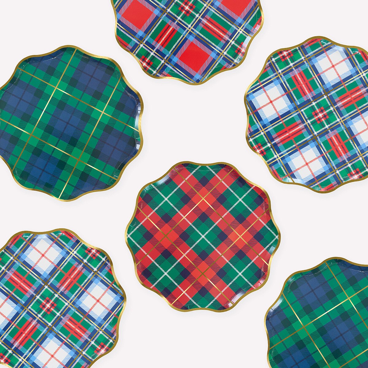 Six scalloped-edge paper plates with gold trim, arranged on a white background. Each plate features a different tartan plaid pattern in green, blue, red, and white.