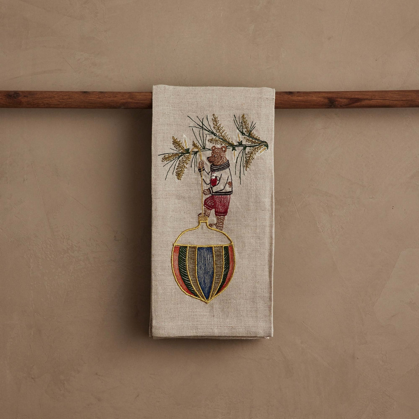 Decorative towel with embroidered design of a bear and Christmas elements on a wooden rod.
