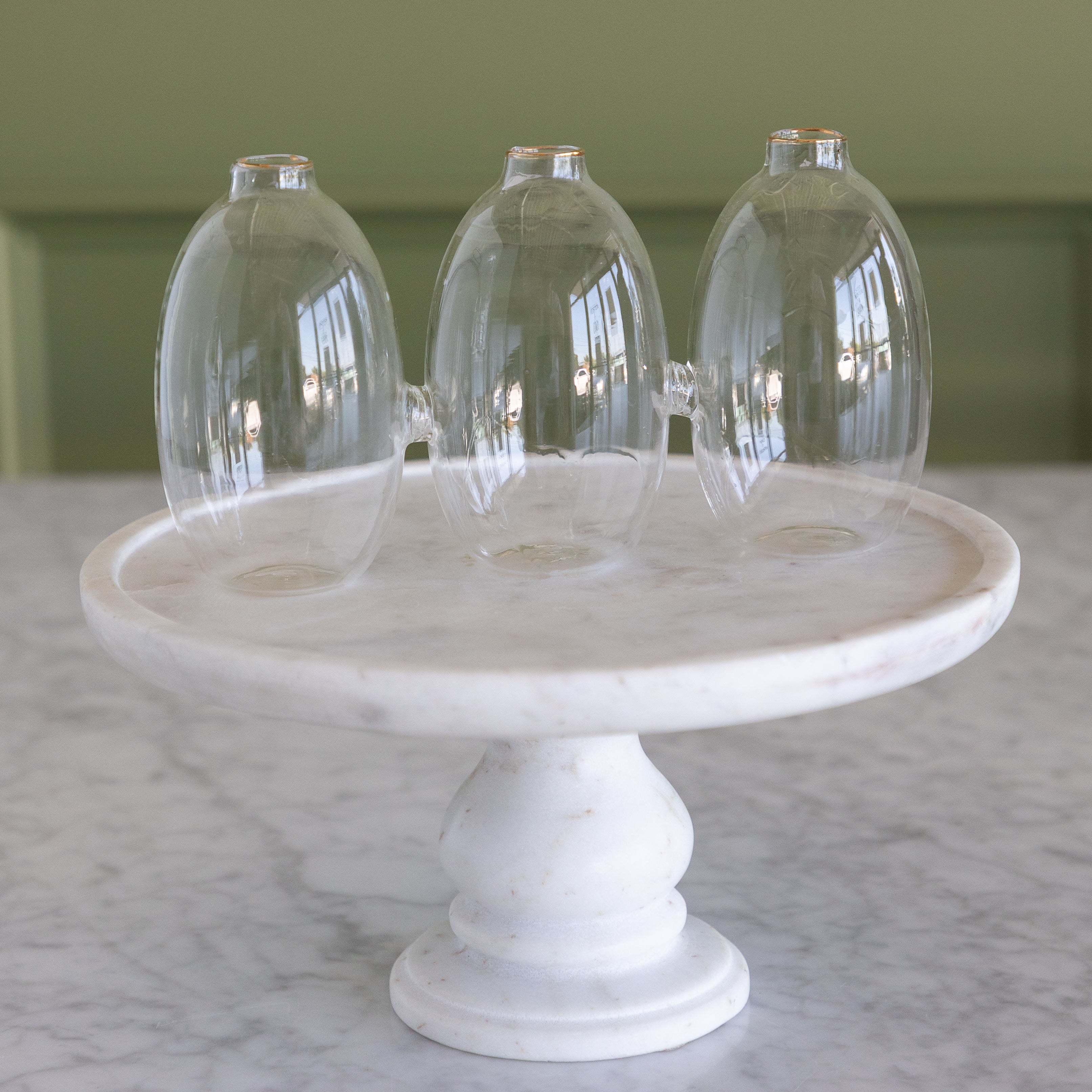 Vase with 3 cylindrical sections that are all attached together. The vase is on a marble pedestal.