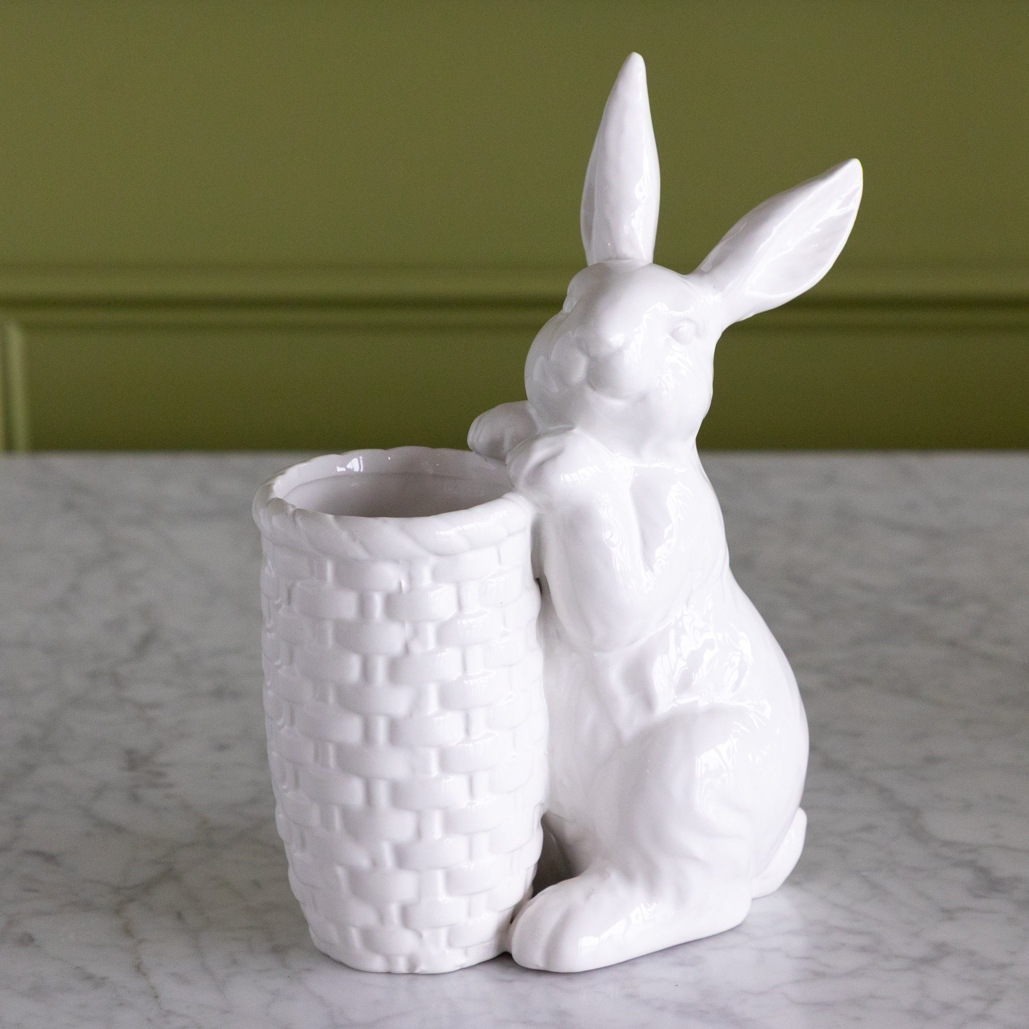 White ceramic rabbit-shaped planter on a marble surface with a green wall background.