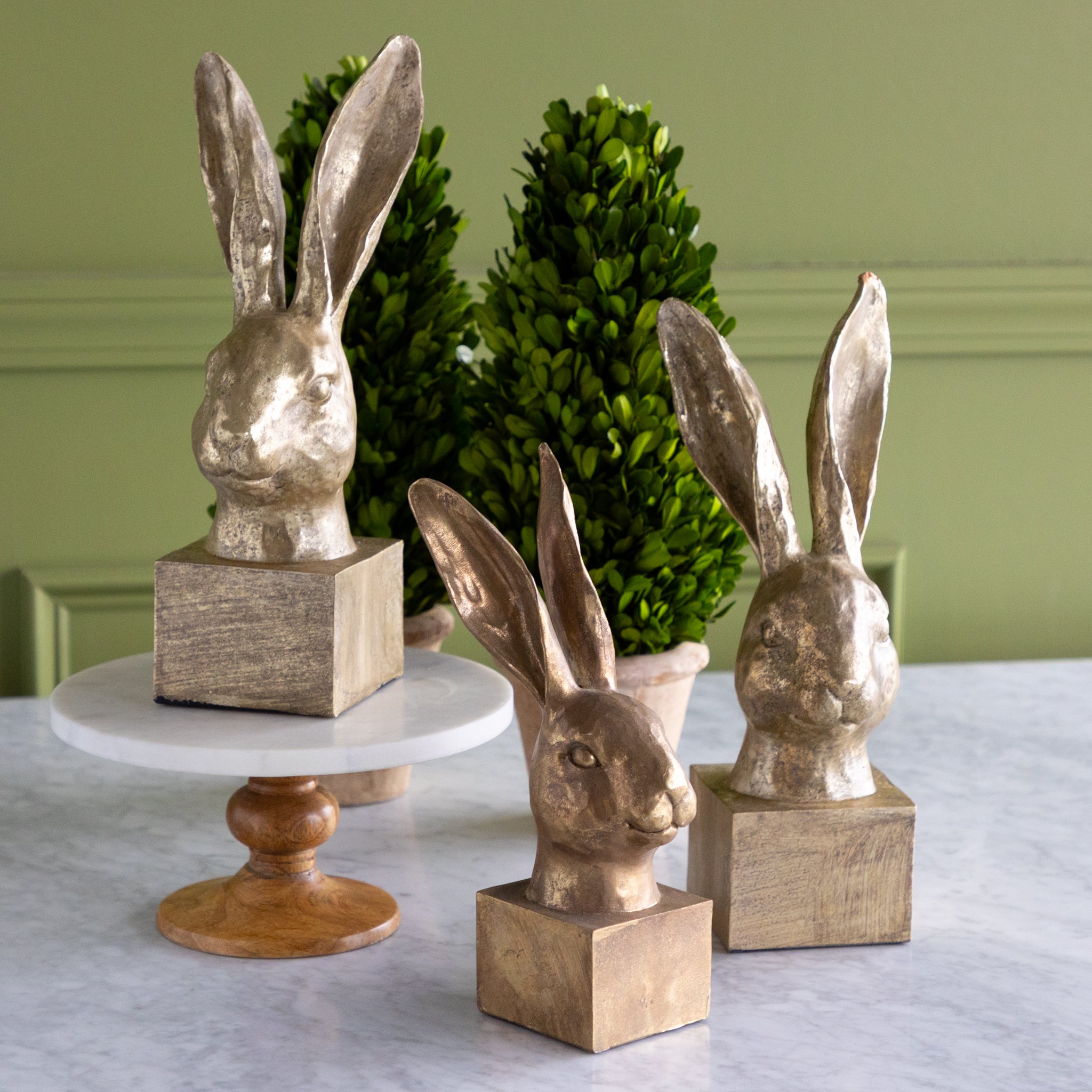Decorative rabbit heads on stands with a green wall background.