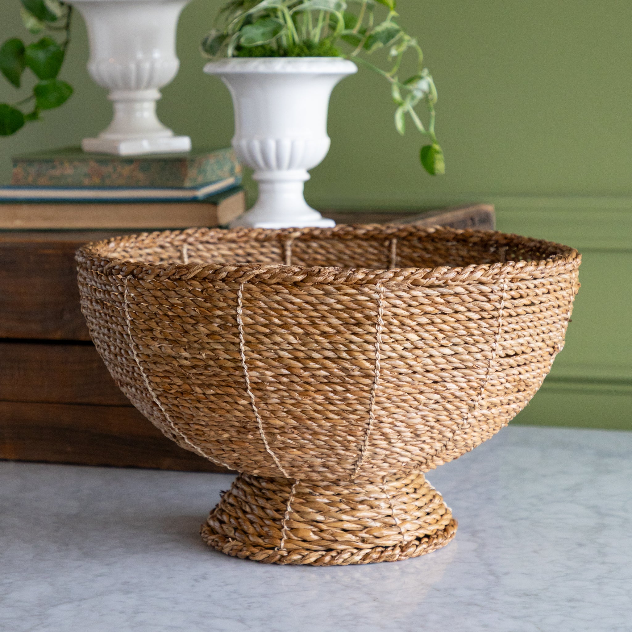 Woven basket on a surface with a green wall and books in the background.
