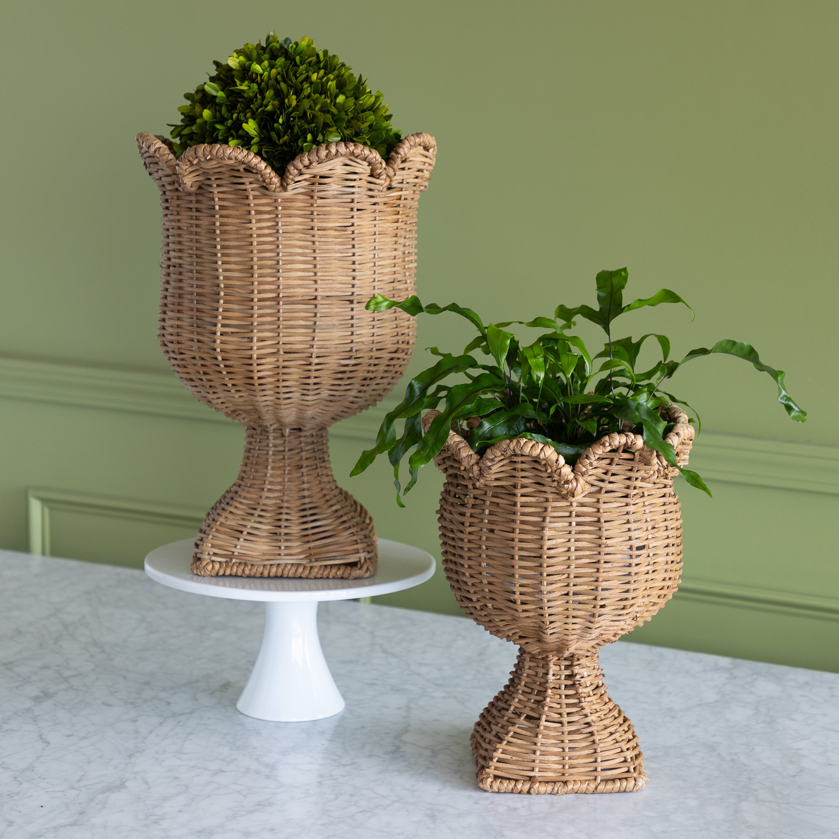 Woven scalloped urn on a marble table with a green background.