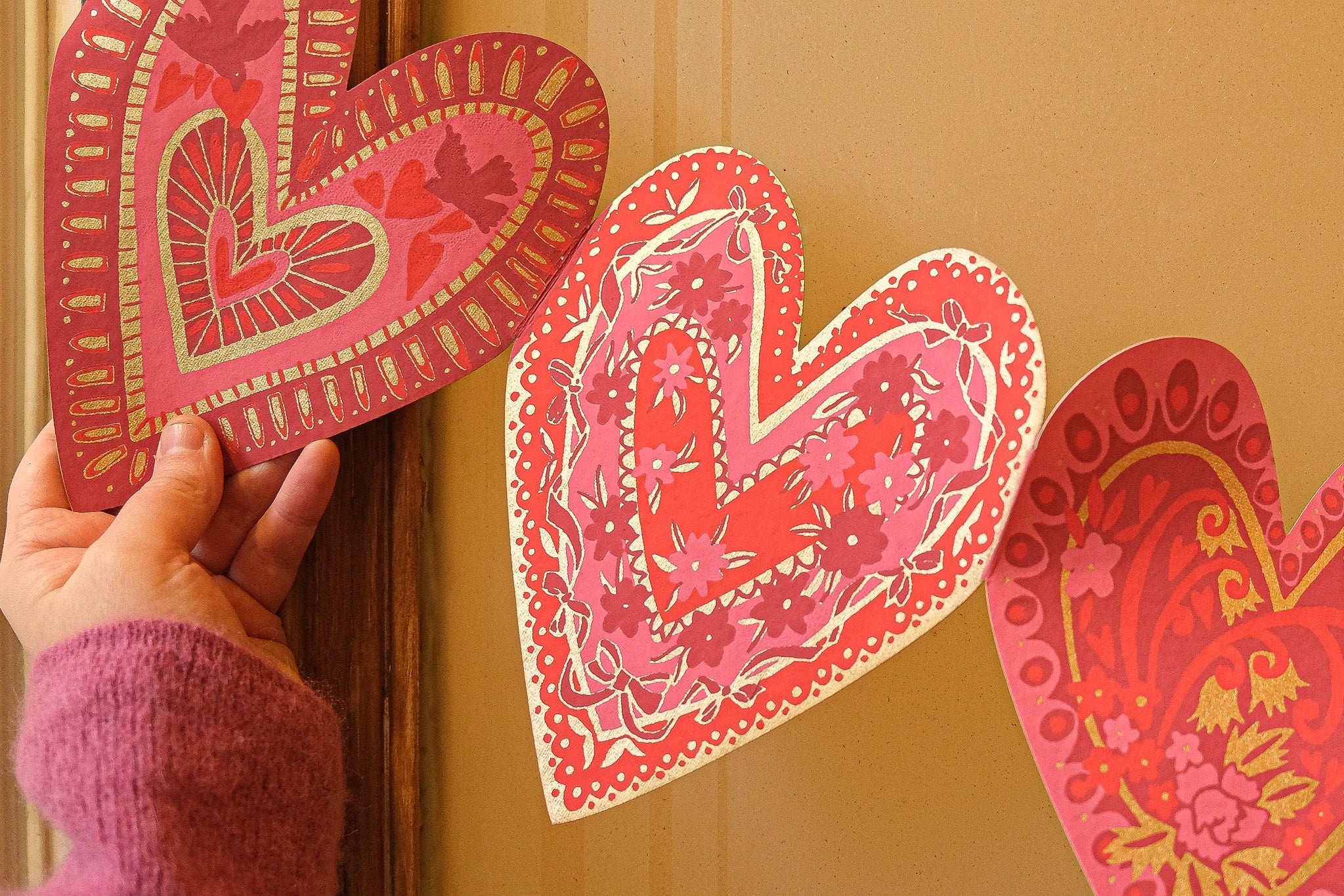 Decorative heart-shaped garland with intricate patterns on a beige wall.
