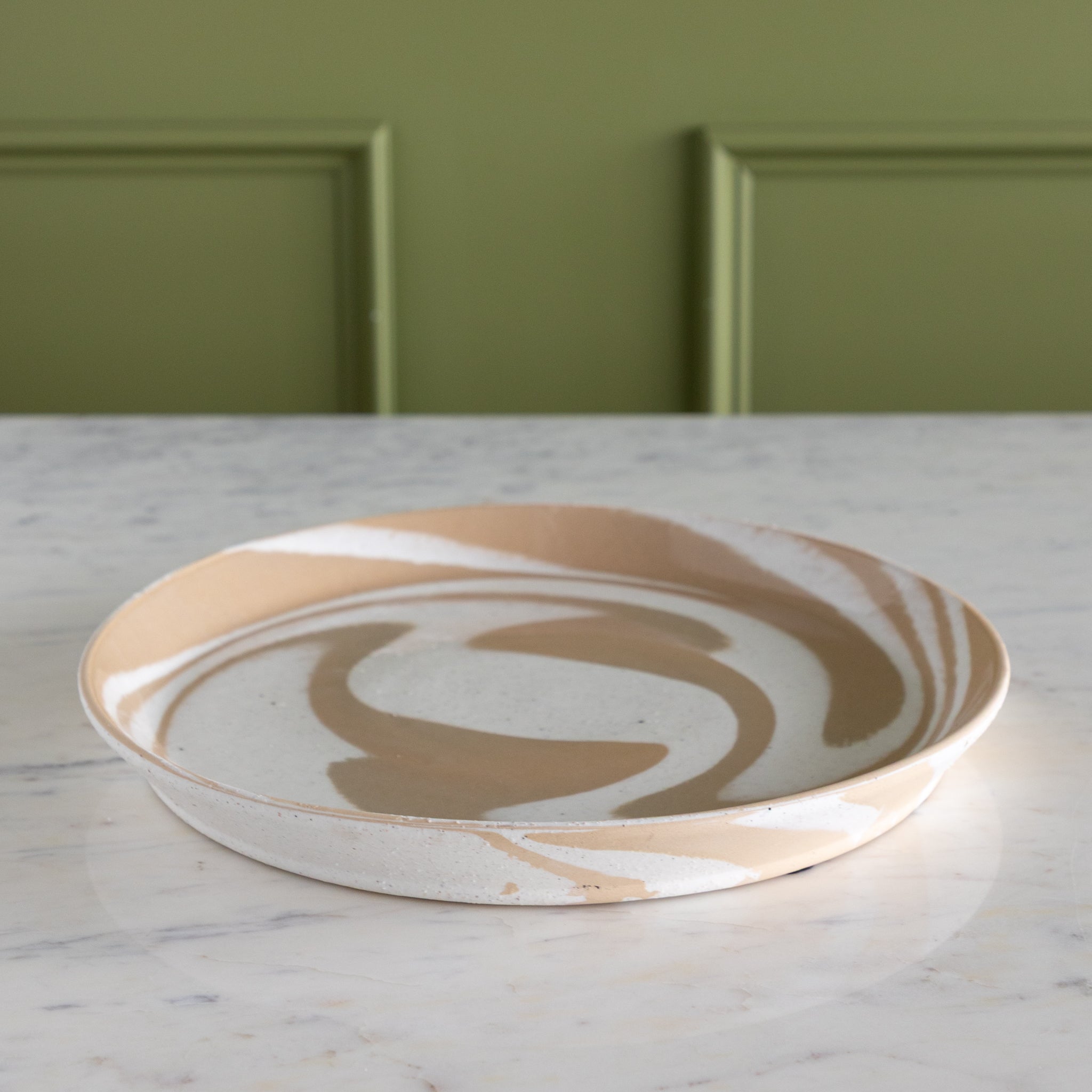 Marbled ceramic plate on a marble surface with a green panel background.