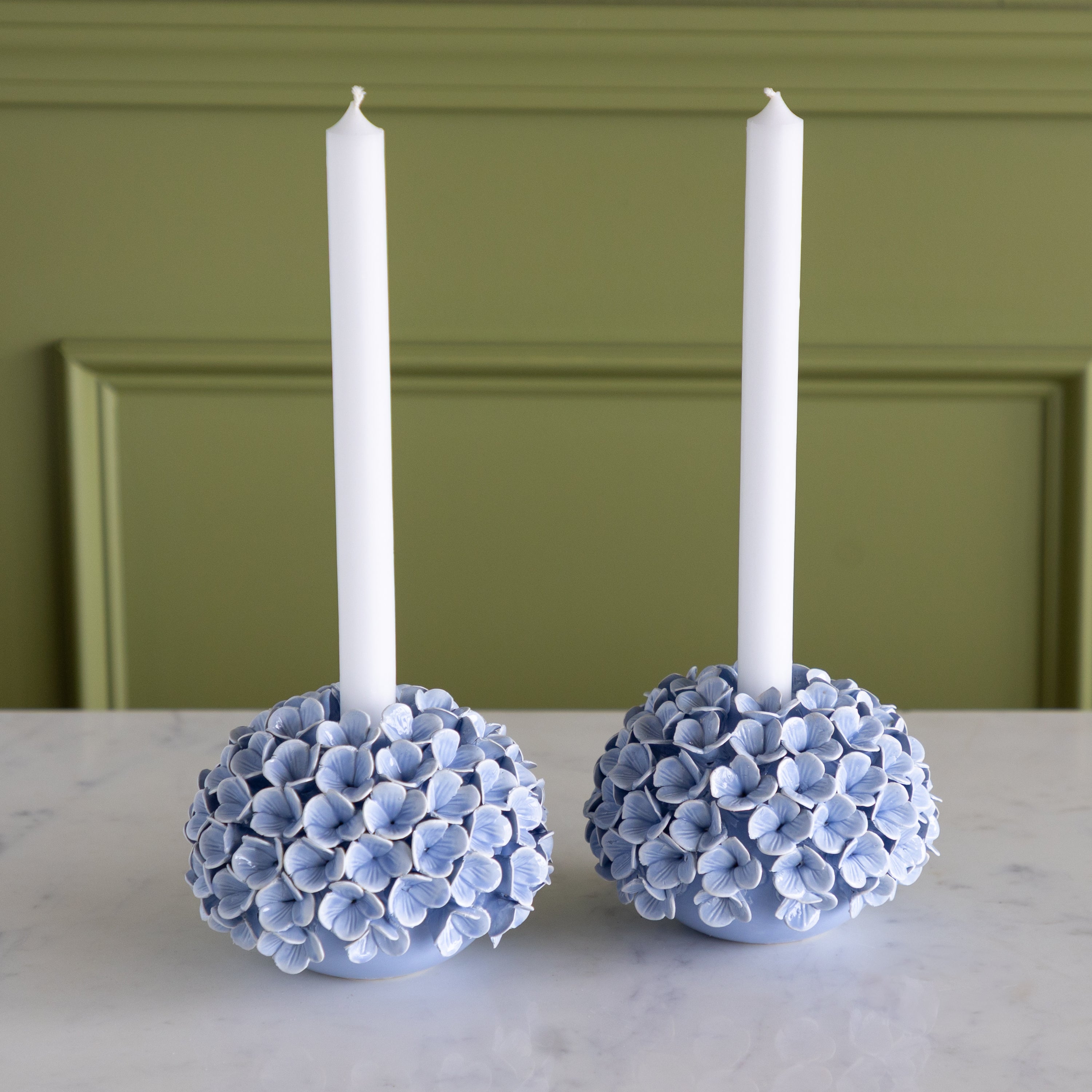 Two decorative candle holders with floral designs on a marble surface.