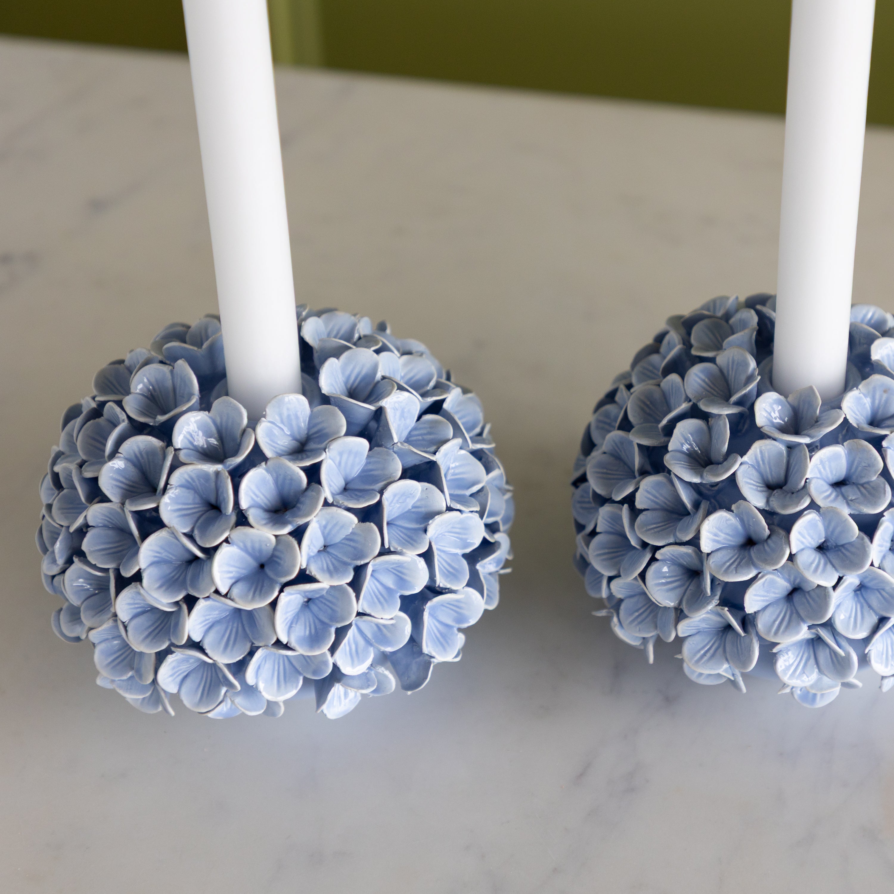 Decorative candle holders with blue flower-like designs on a marble surface.