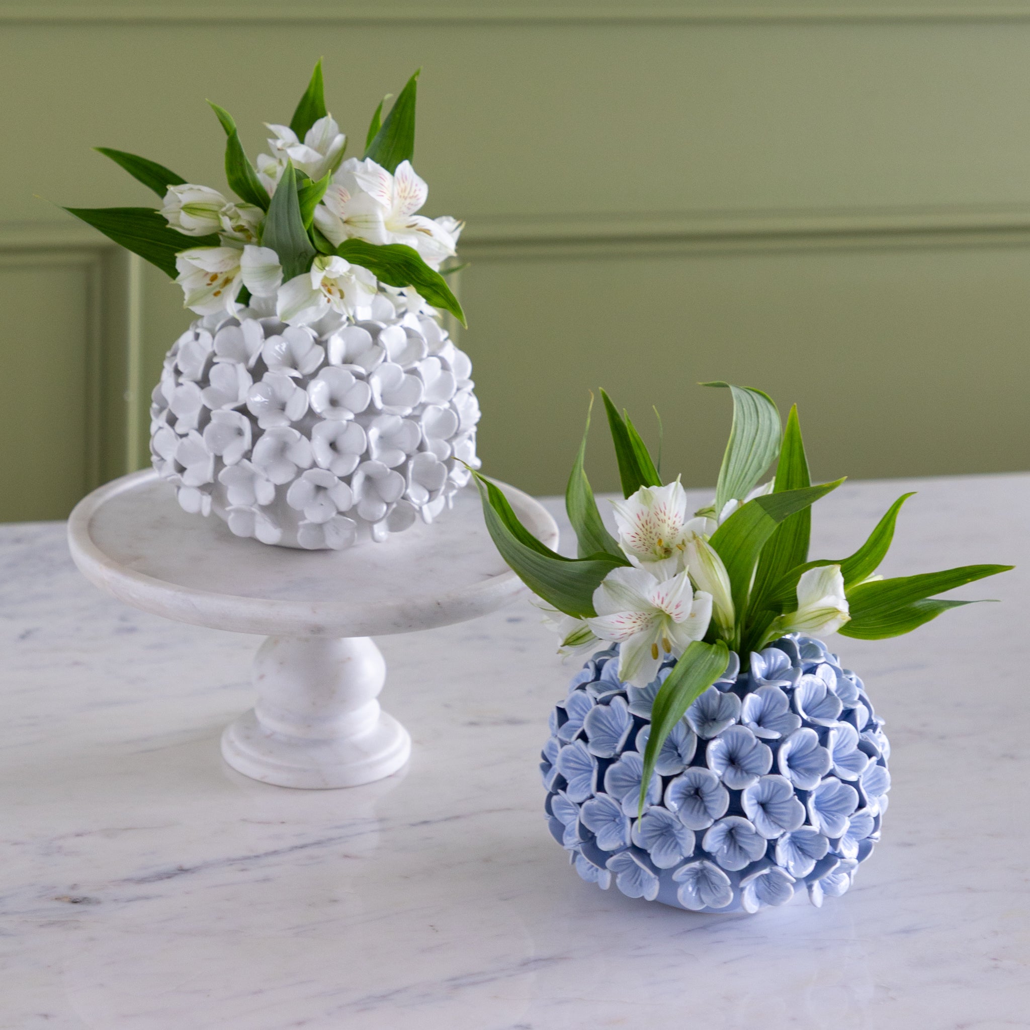 Two decorative vases with floral arrangements on a marble surface.