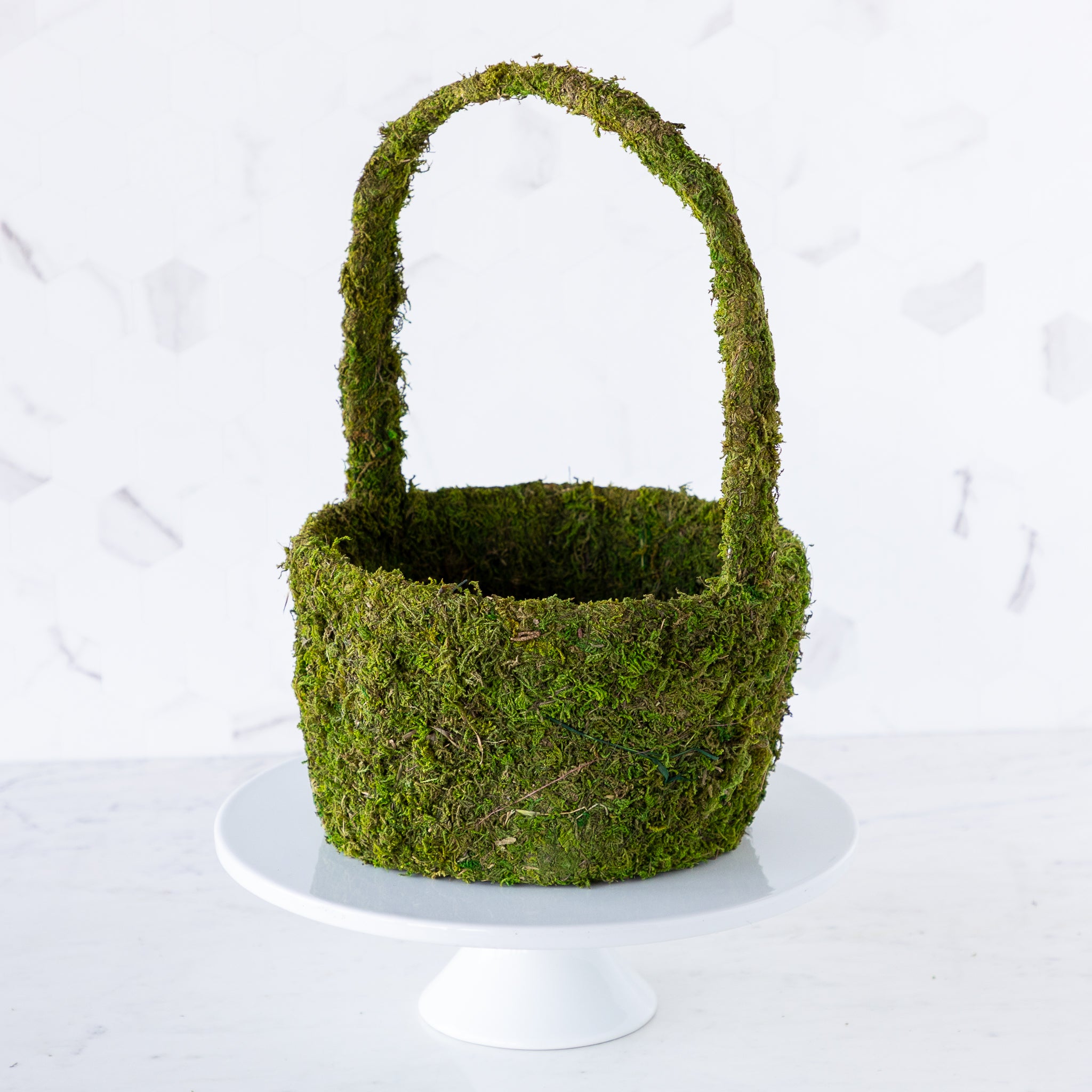 A large Decorative Moss Basket displayed on a cake stand.