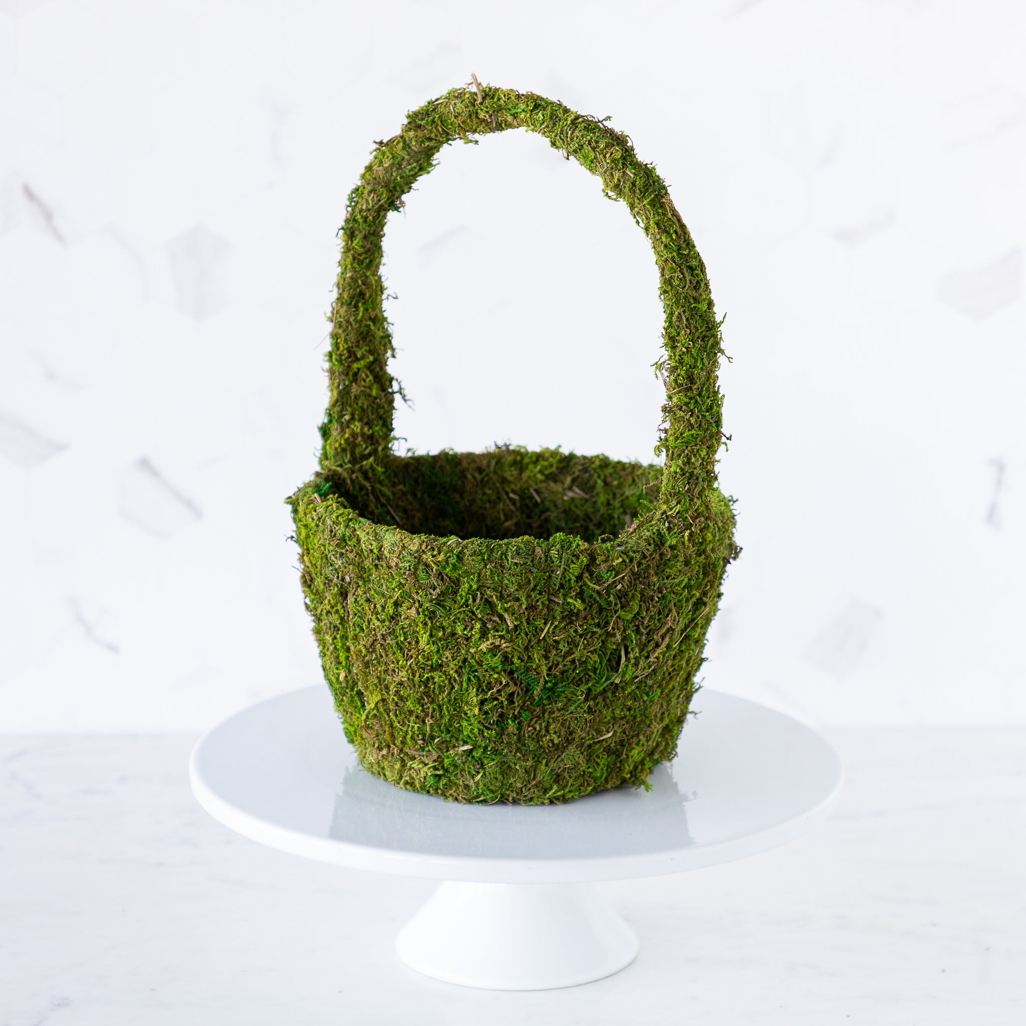 A medium Decorative Moss Basket displayed on a cake stand.
