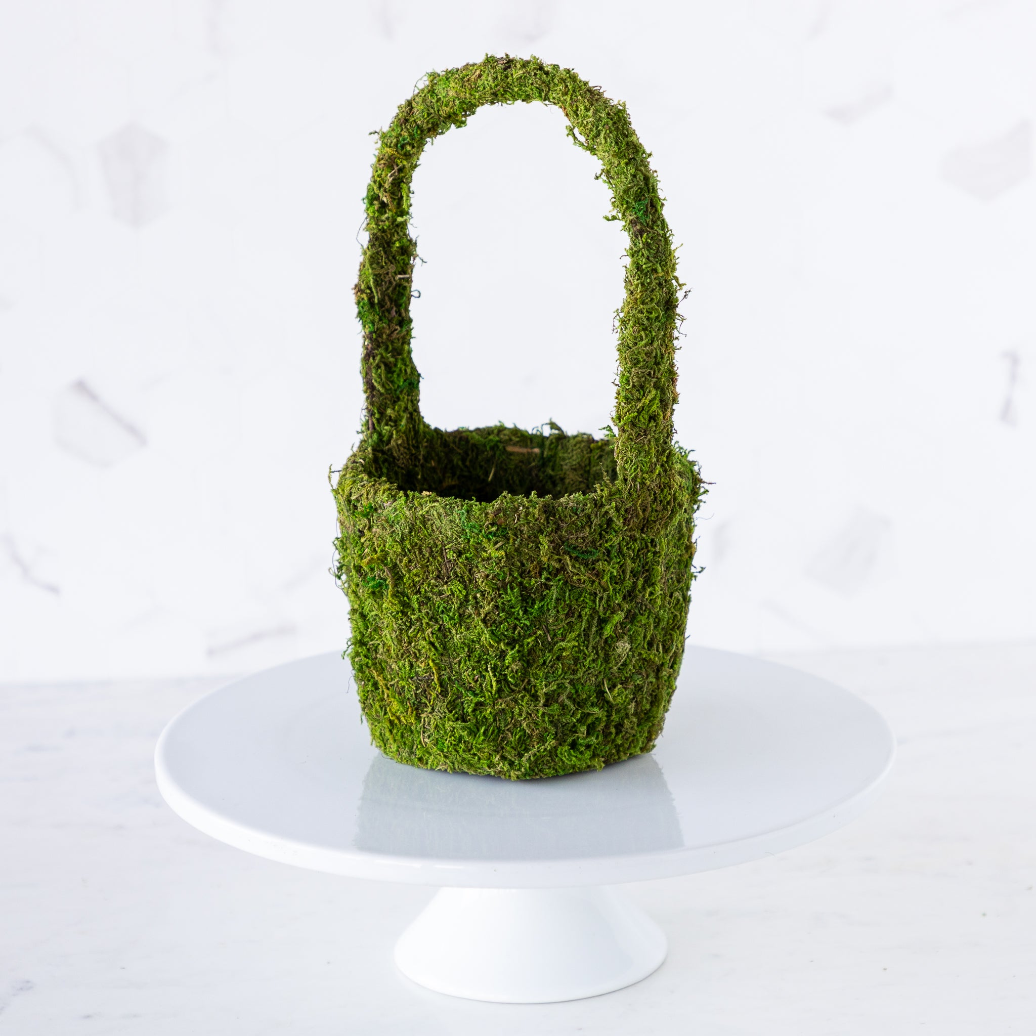 A small Decorative Moss Basket displayed on a cake stand.