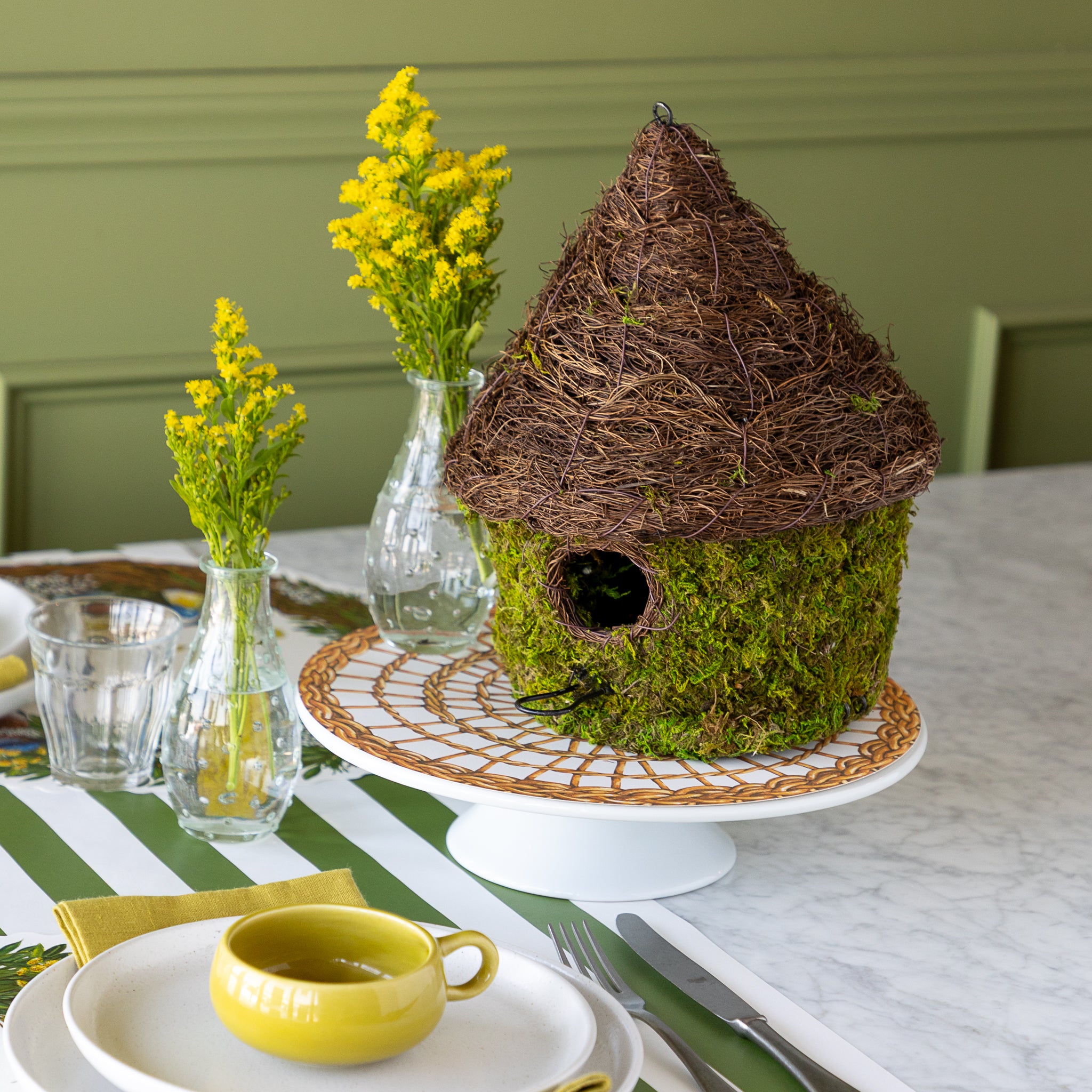 Bungalow Bird House made with moss on a table setting.