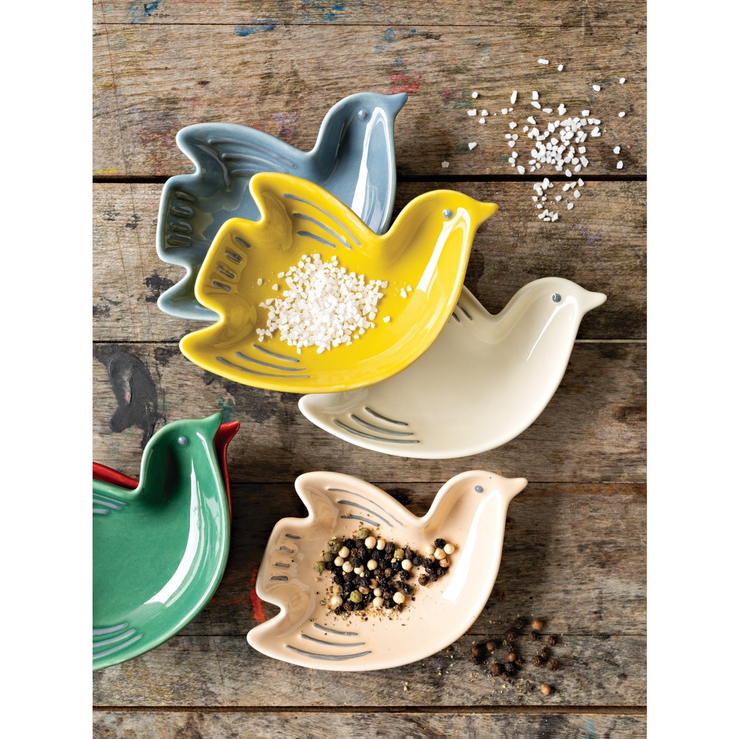 Set of colorful ceramic bird-shaped bowls on a wooden surface.