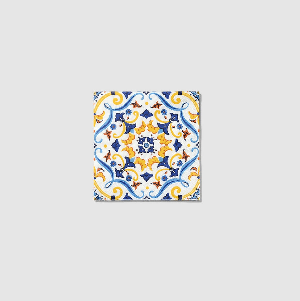 La Dolce Vita Paper Napkin featuring a symmetrical blue, yellow, and orange floral and scroll pattern on a white background.
