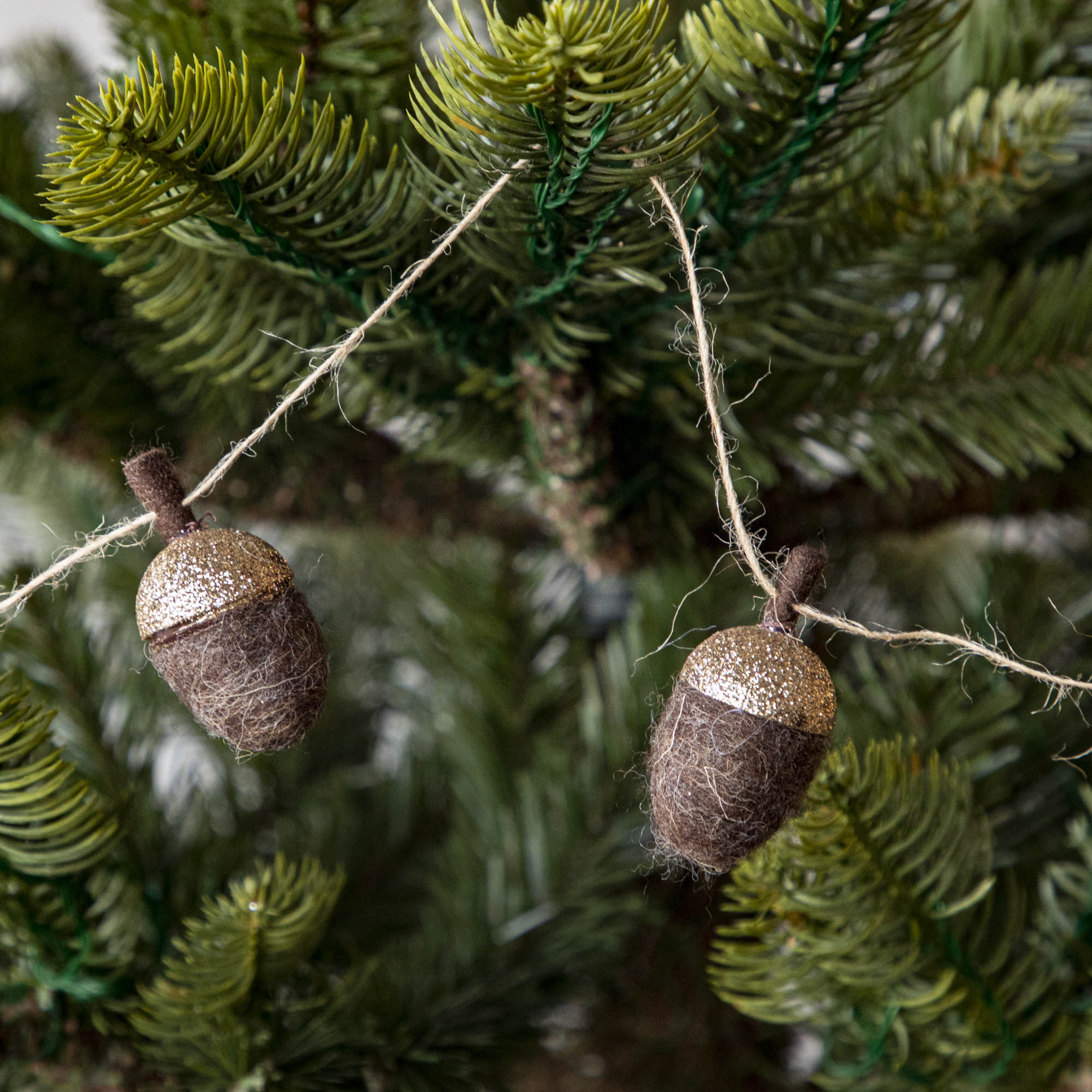 Close up of woolen acorn garland in a tree showing its glittered top .