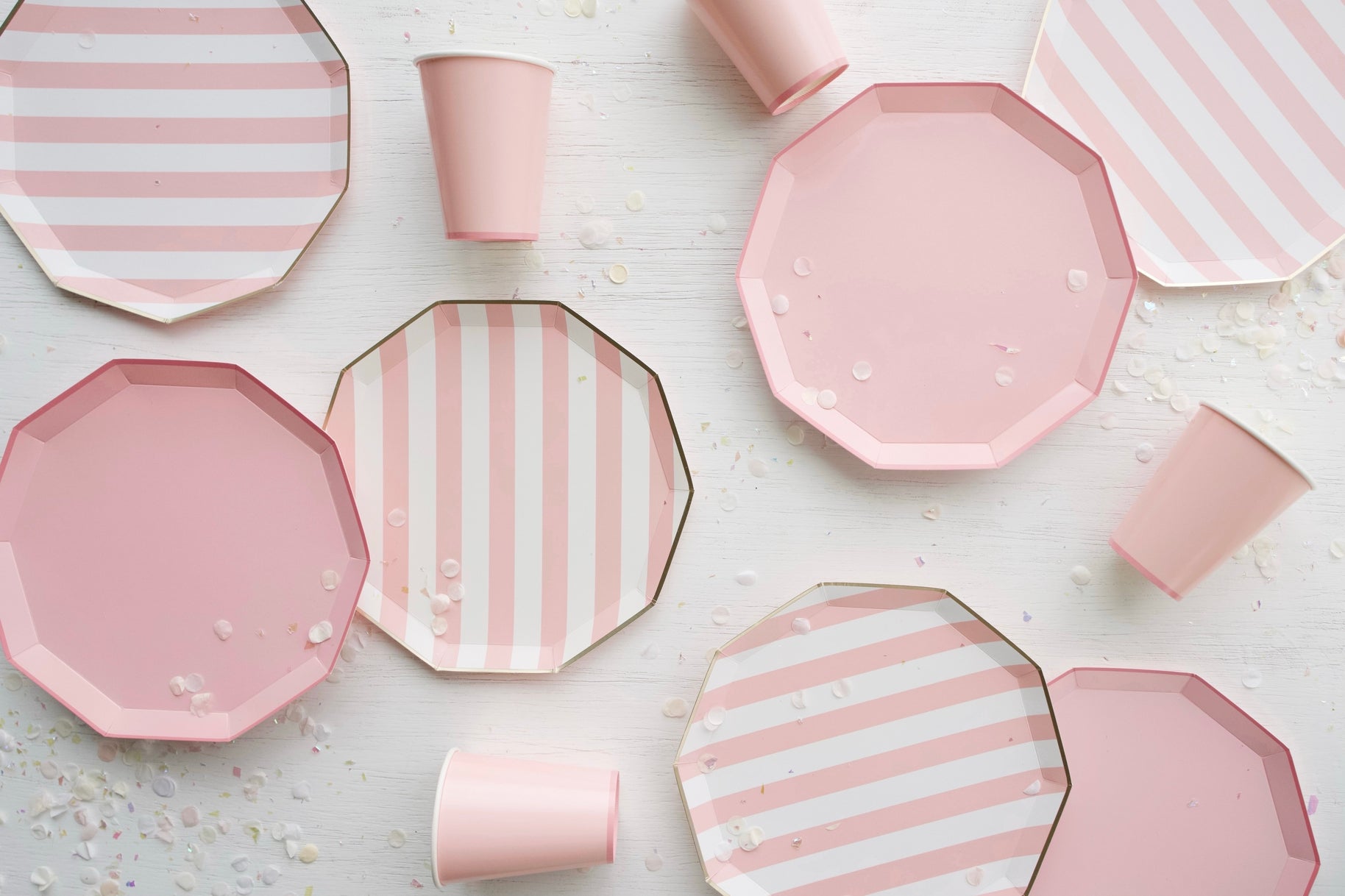 Pink and white striped plates and cups on a light surface.