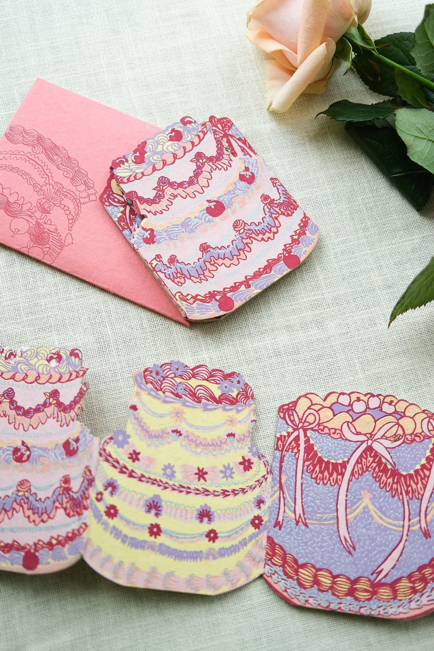 Decorative cake-shaped cards with frosting details on a textured surface.