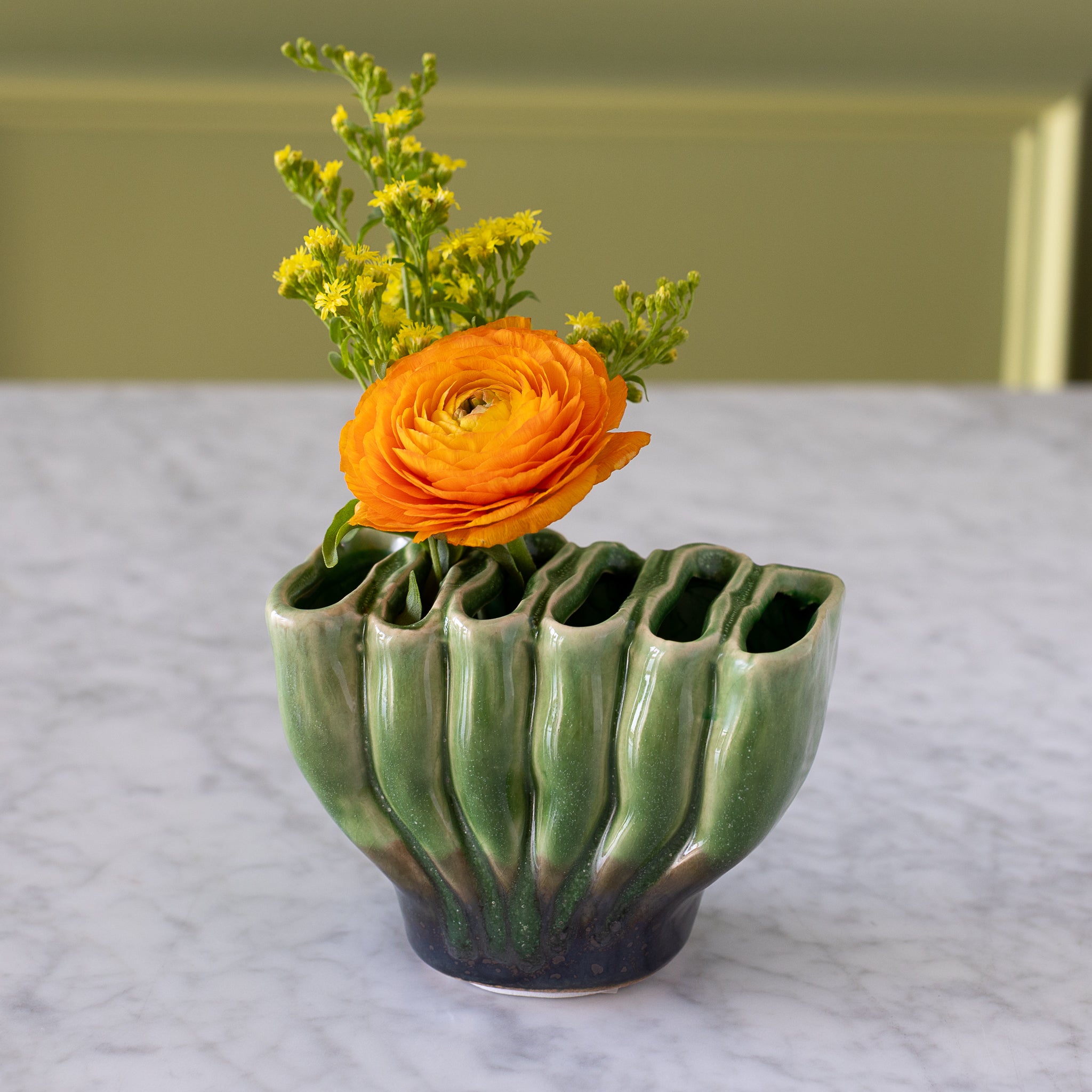 6-hole Ceramic Fakir Green Vase with a flower in it.