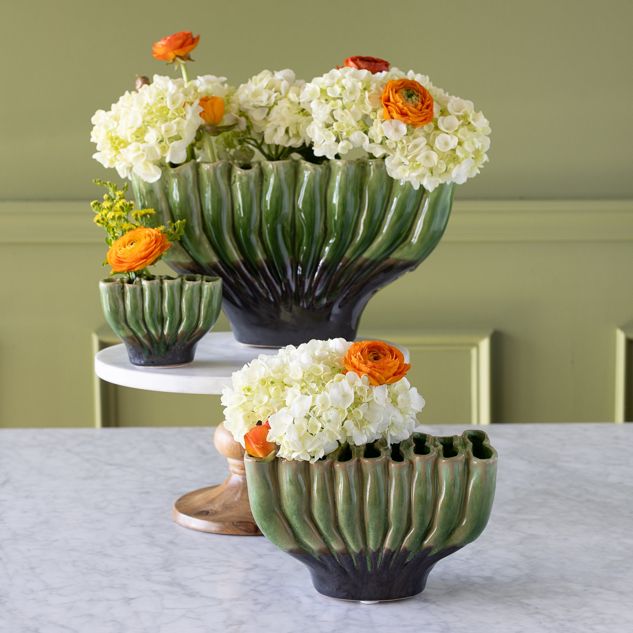 Ceramic Fakir Green Vases in three sizes with flowers in them.