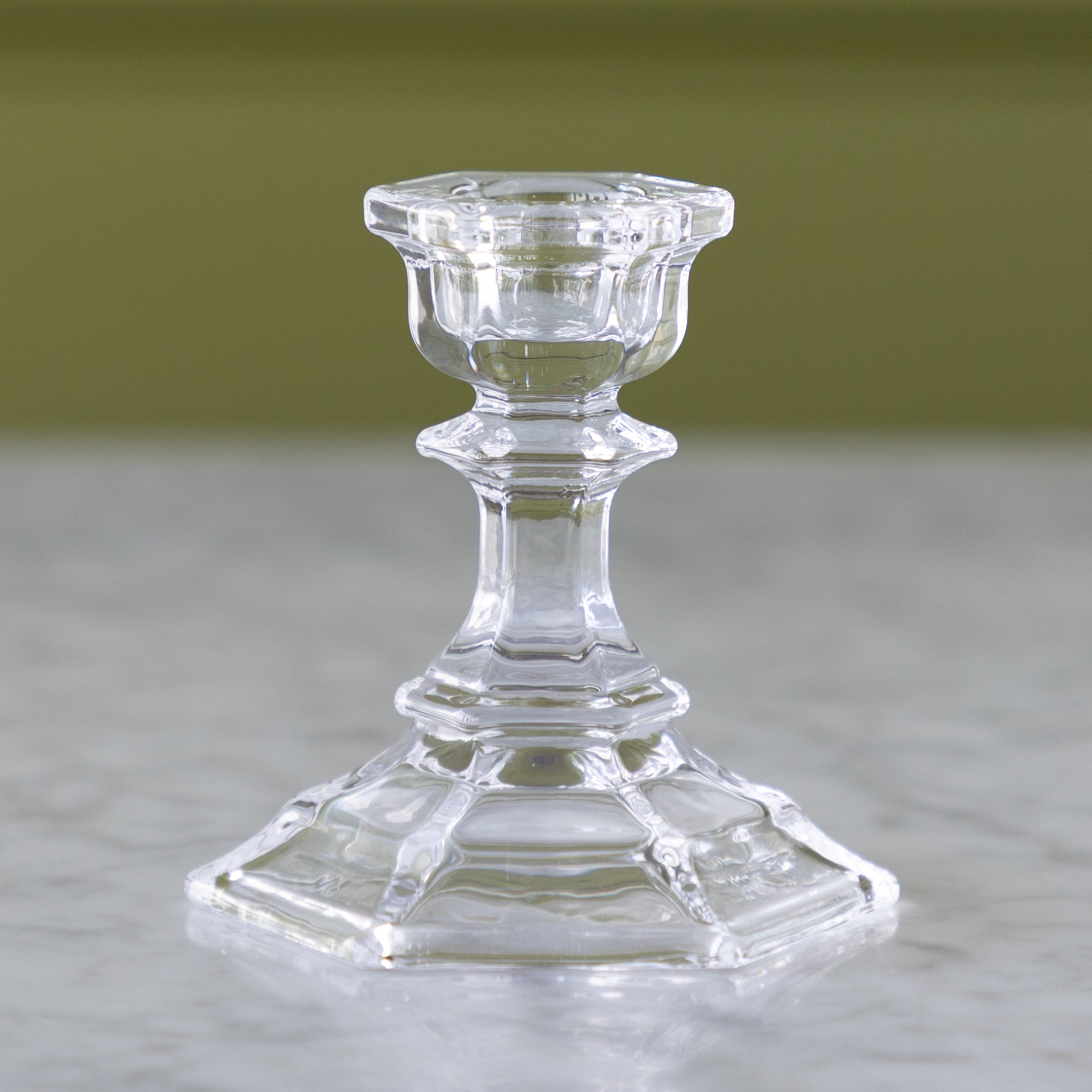 Clear glass candlestick on a neutral background.