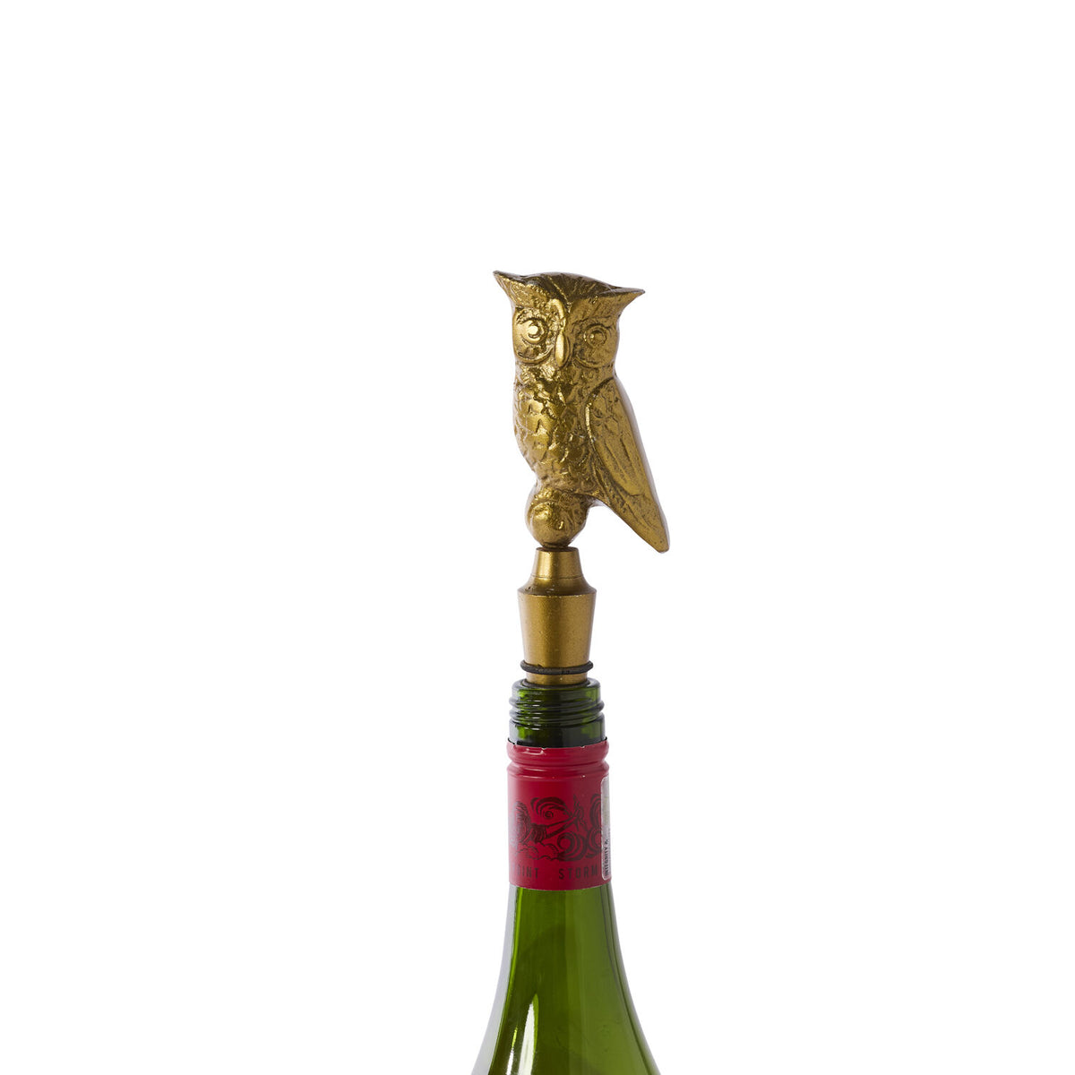 Gold owl-shaped bottle stopper on a wine bottle with a white background.