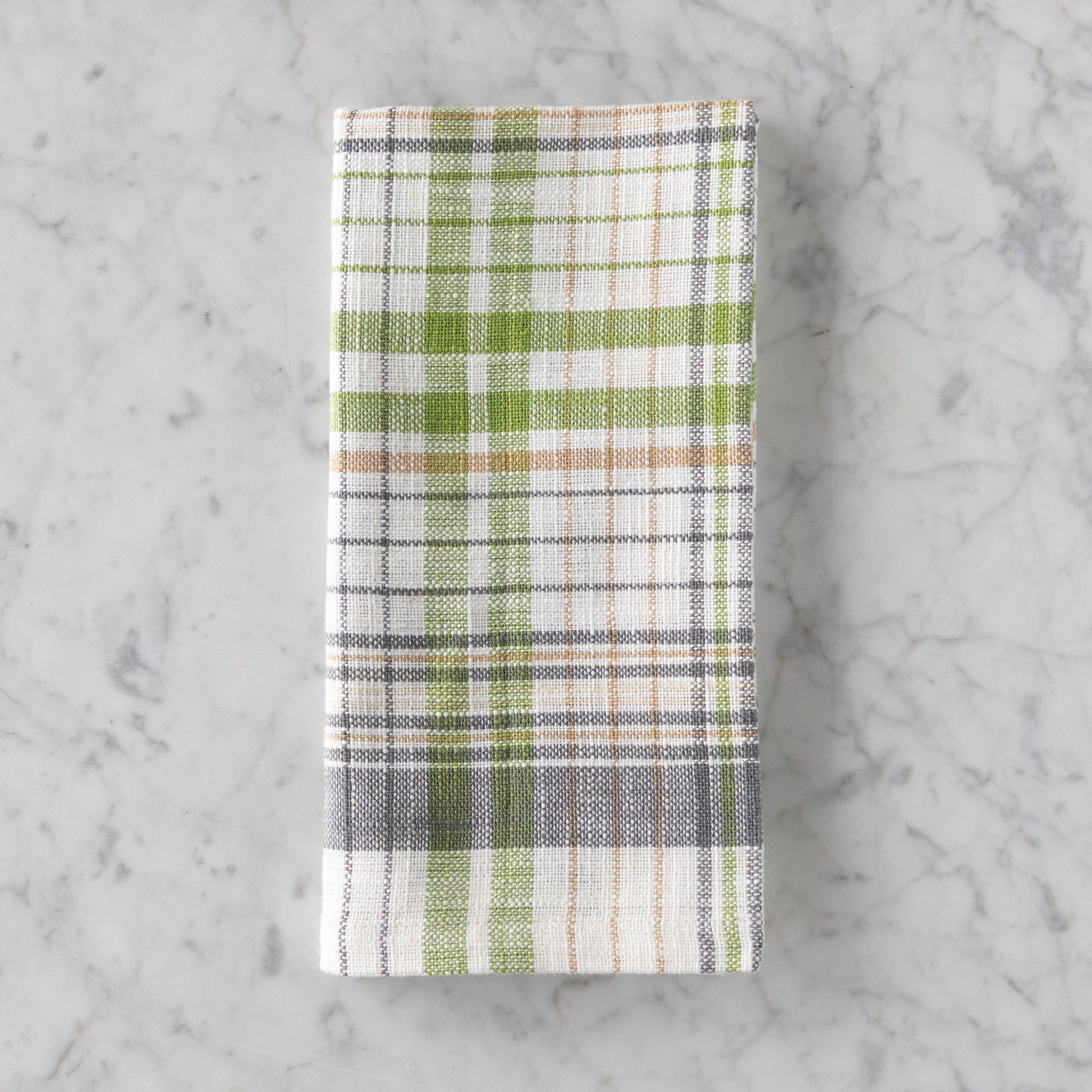 Plaid towel with green, white, and brown pattern on a marble surface.
