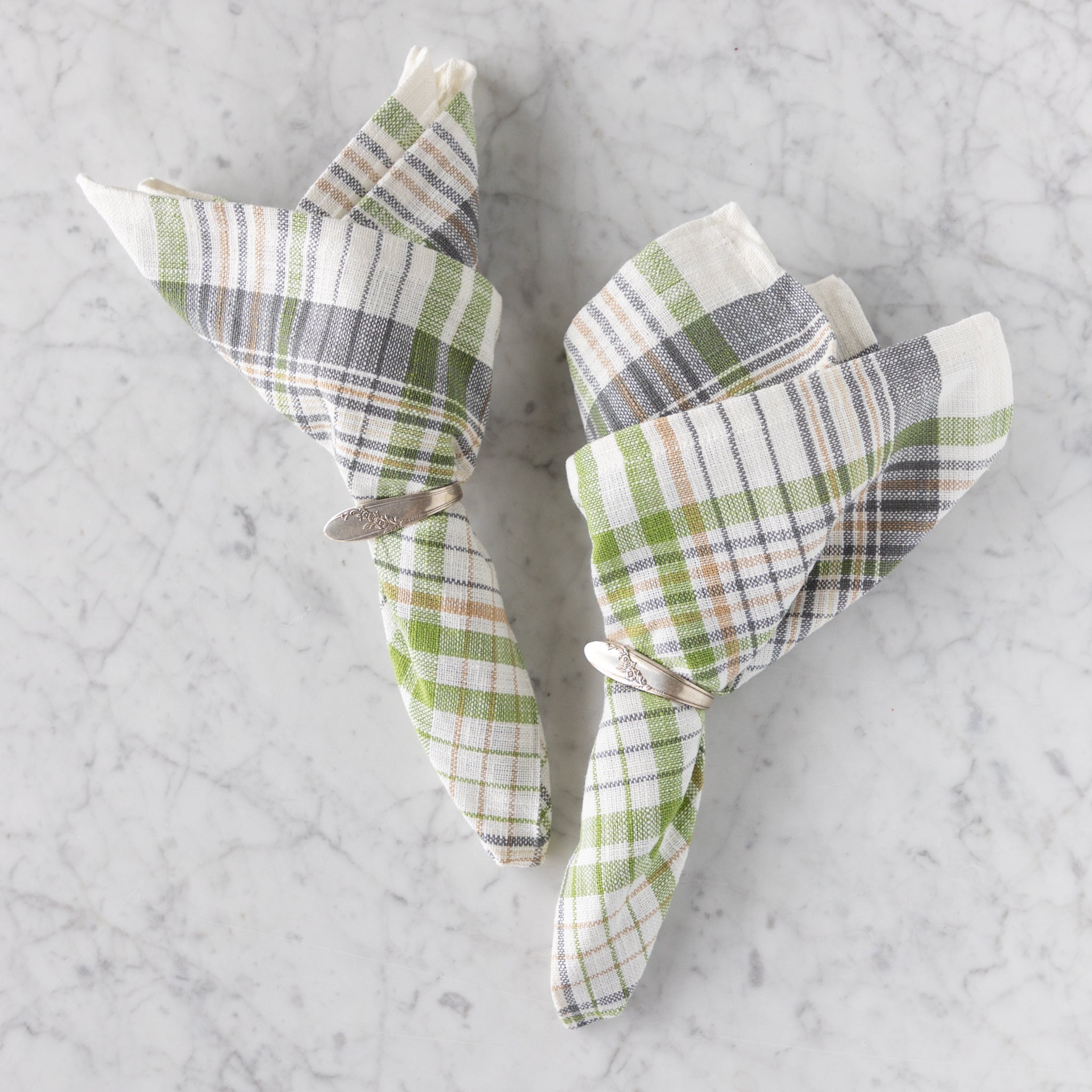 Plaid napkins folded into triangles on a marble surface.