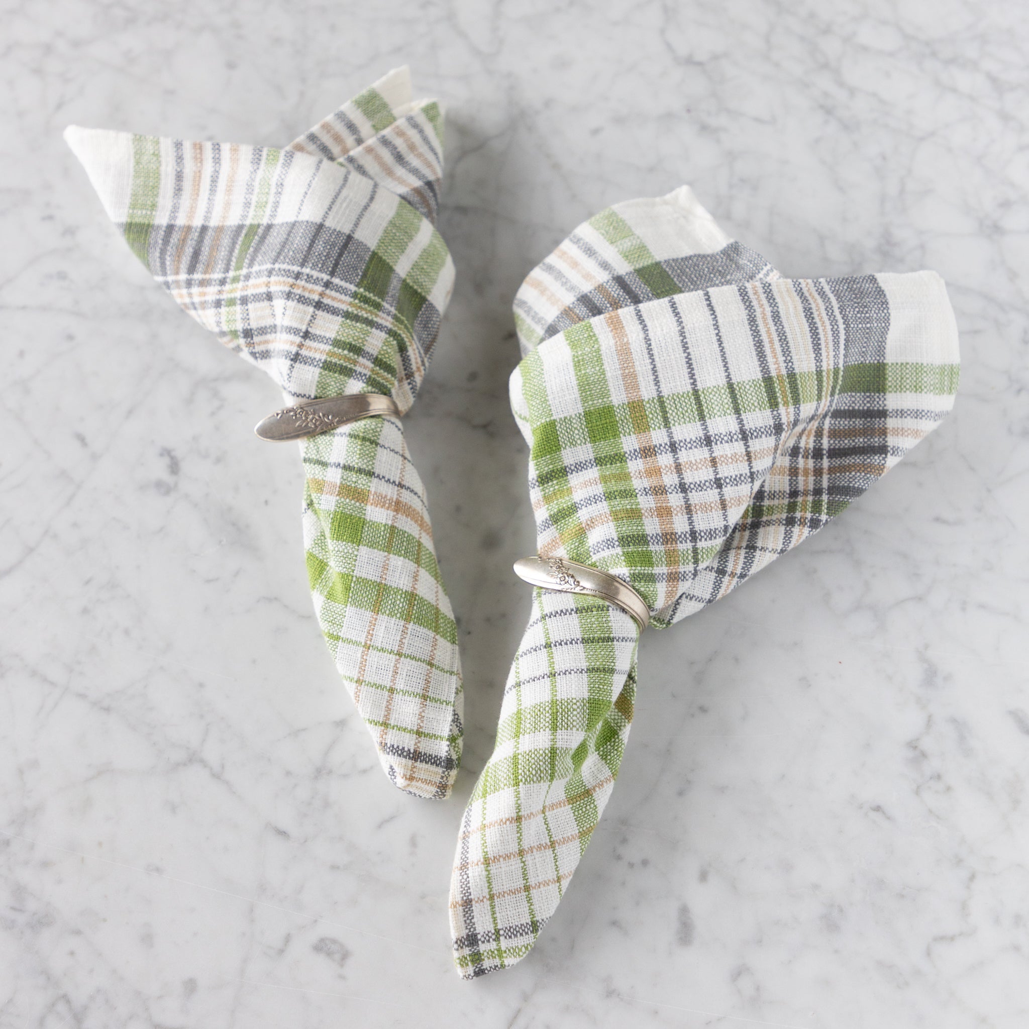 Two folded checkered napkins on a marble surface.