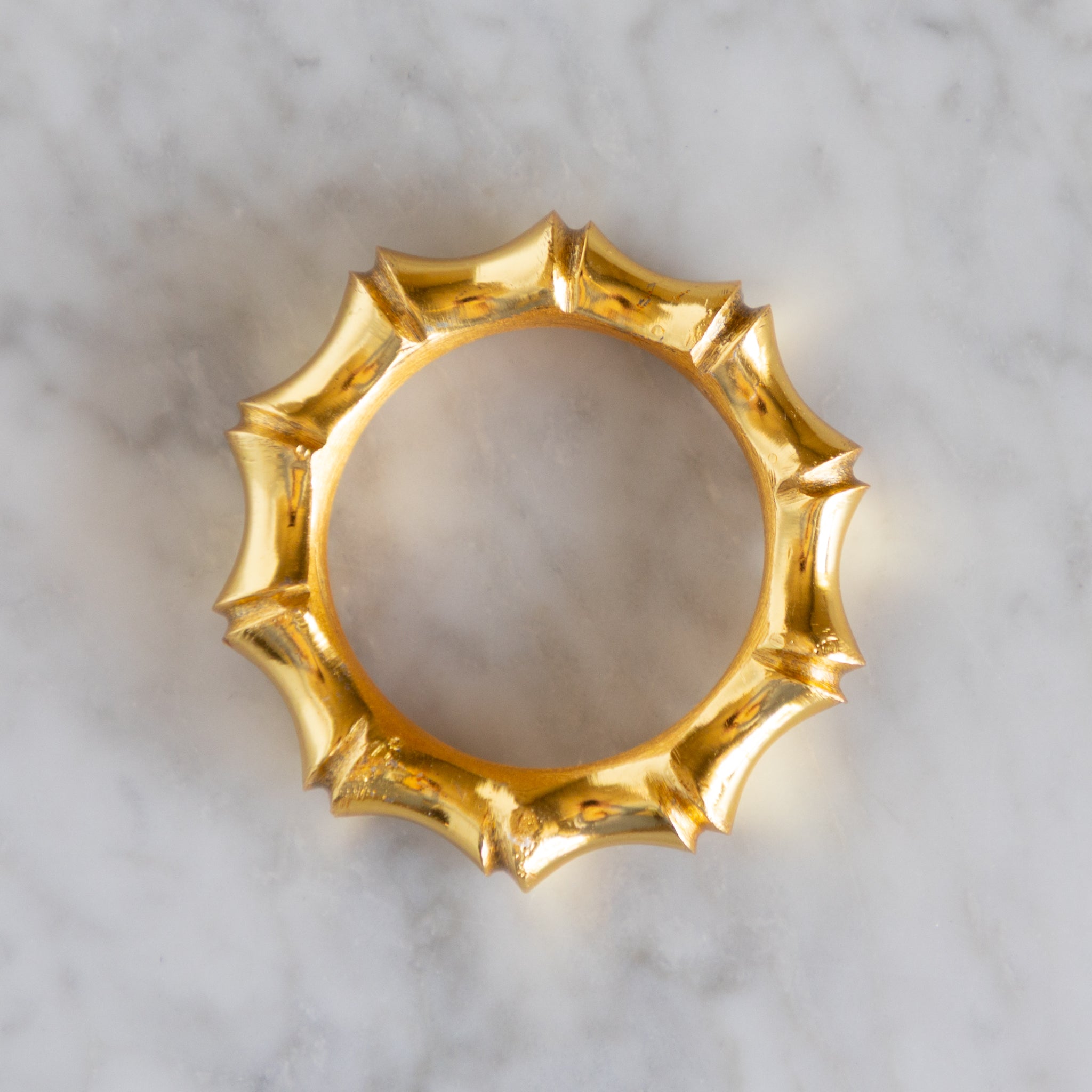 Gold decorative napkin ring on a marble surface.