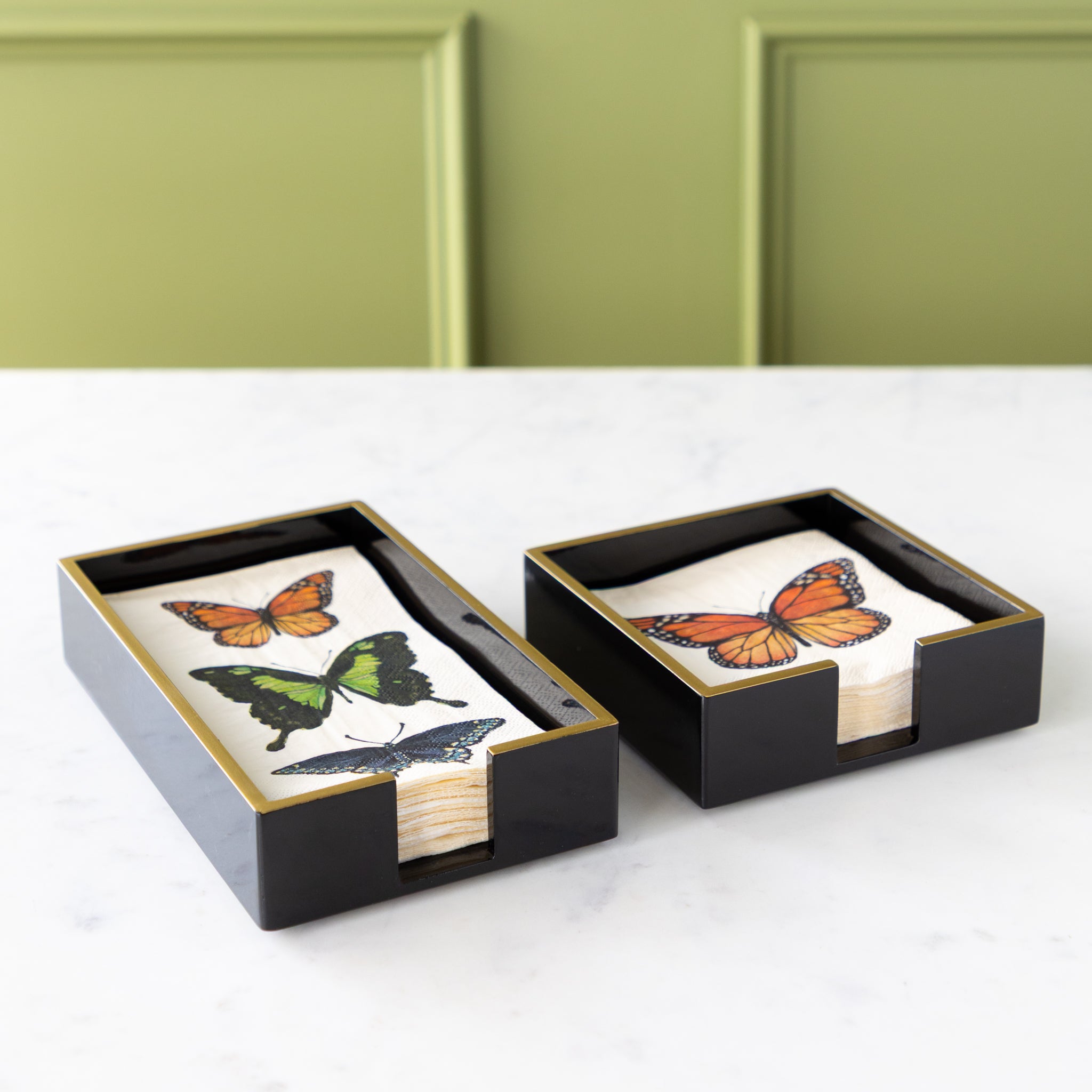 Black Napkin Holders with Gold Trim in a cocktail and guest size with Hester & Cook Butterfly Napkins in them.