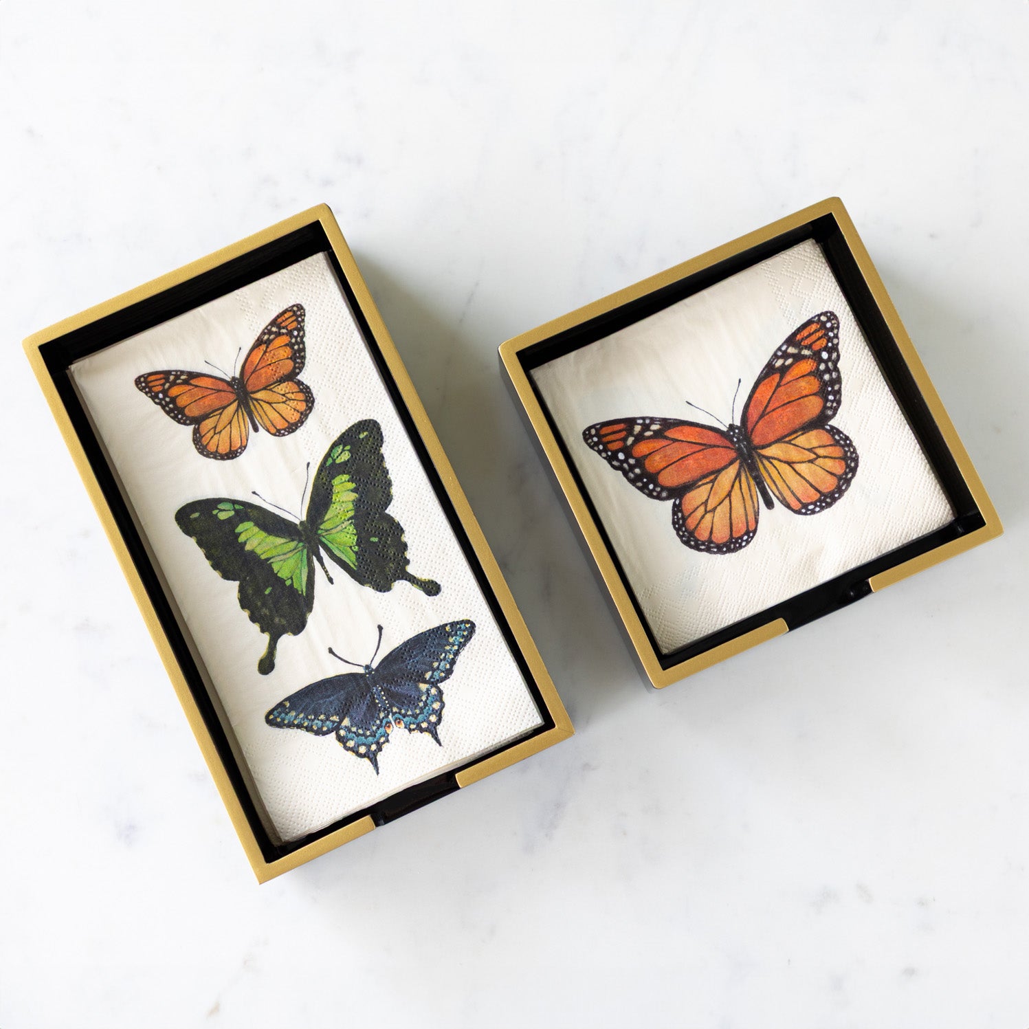 Black Napkin Holders with Gold Trim in a cocktail and guest size with Hester & Cook Butterfly Napkins in them.