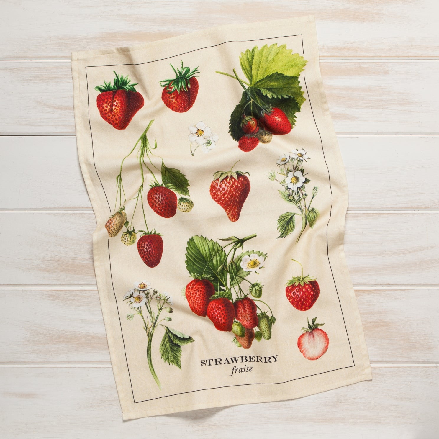 Tea towel with strawberry design on a wooden surface.